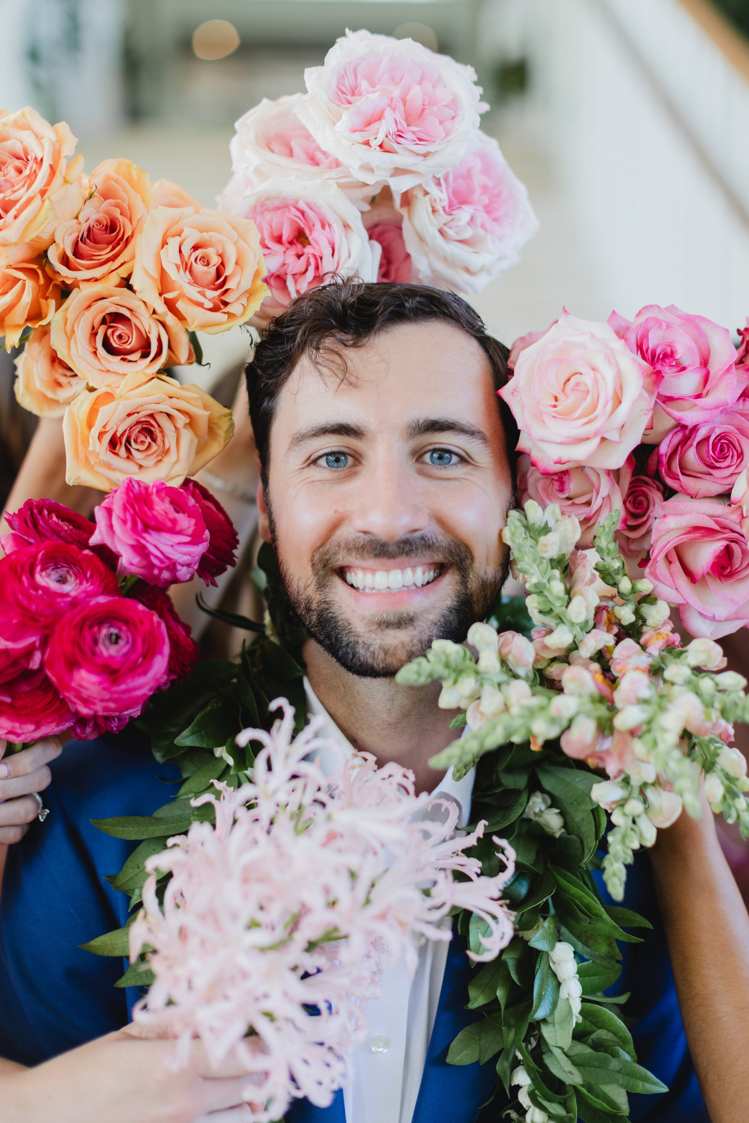 groom surrounded by pink and orange flowers