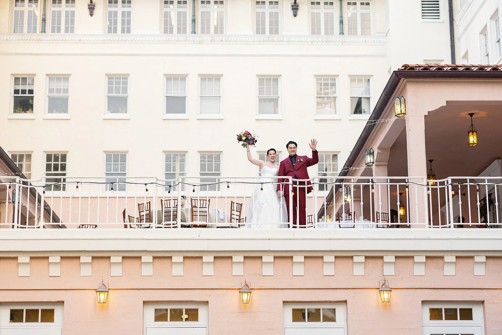 Bride and groom waving from balcony