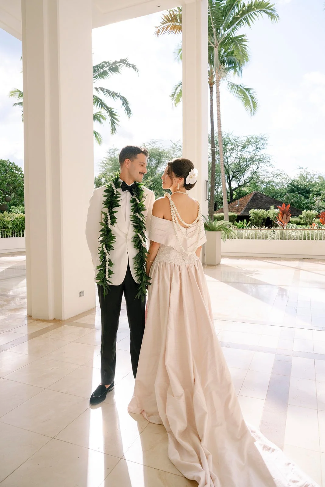 bride and groom looking at each other with lei