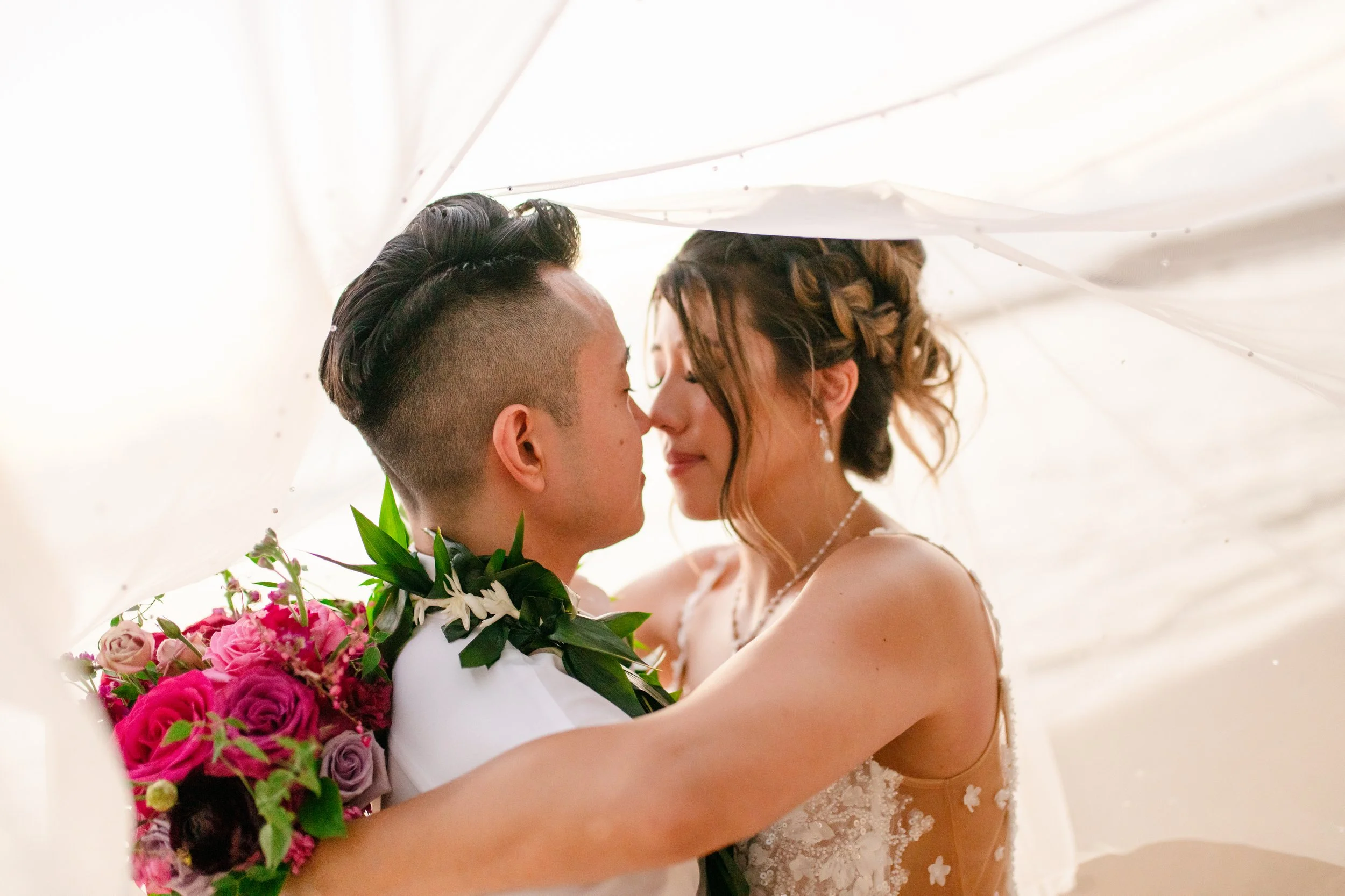 bride and groom under veil on beach