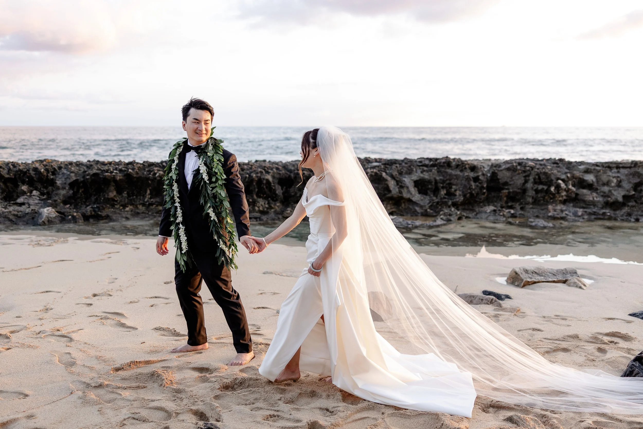 bride and groom holding hands on beach in hawaii