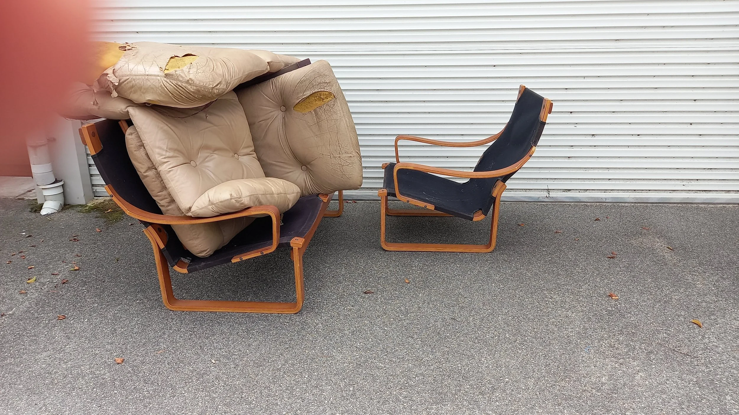 furniture in a bad state of repair in front of a roller door, with ripped cushions