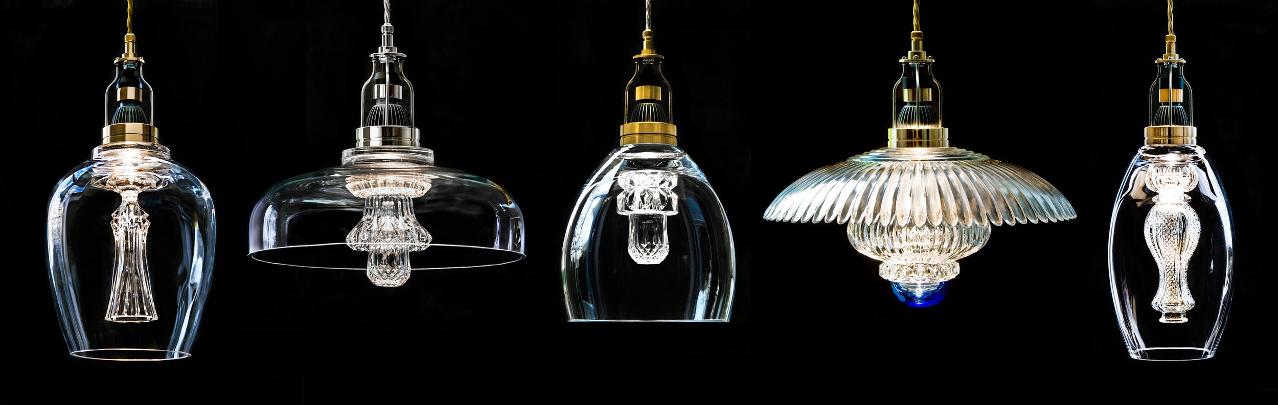 Five designer glass pendant lights with intricate, decorative glasswork and metallic accents, hanging against a black background.