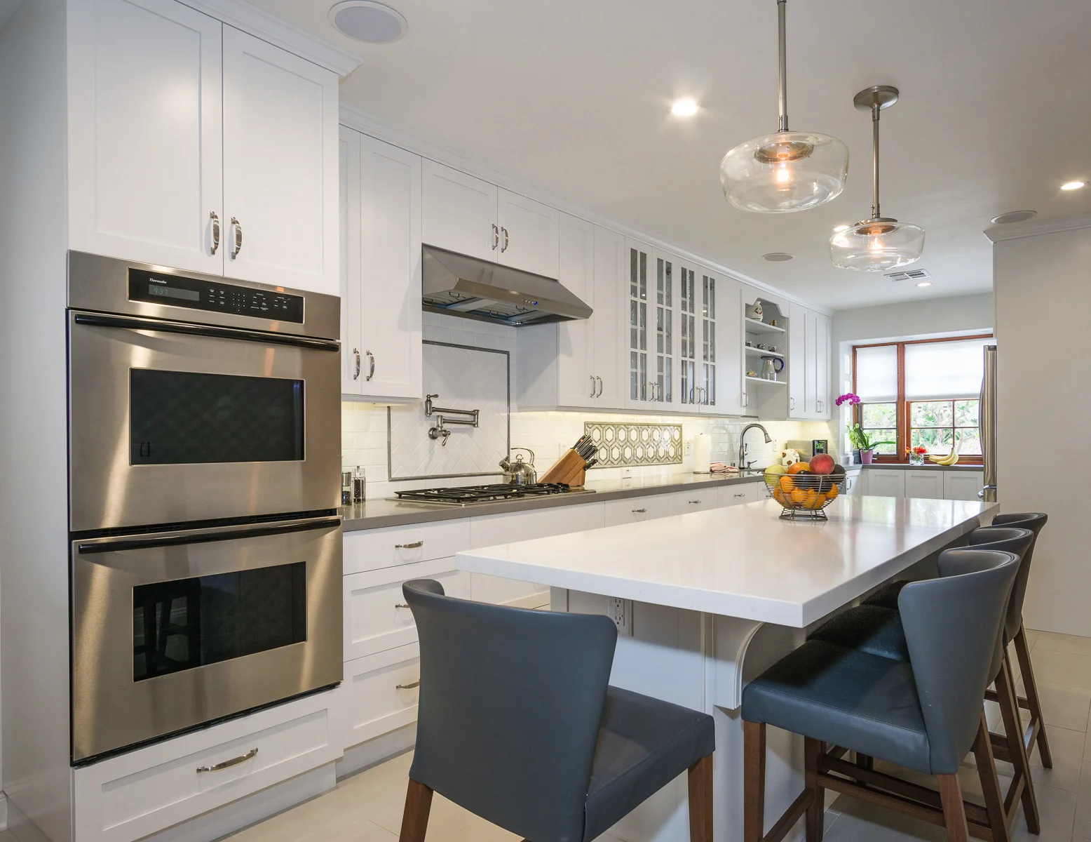 Before this was a chopped up dark bowling alley with multiple angled cabinets creating meandering paths to separate work areas...completely inefficient & pretty ugly. The new remodel opened up the space into a beautifully streamlined and functional galley with an island where the whole family can be together.