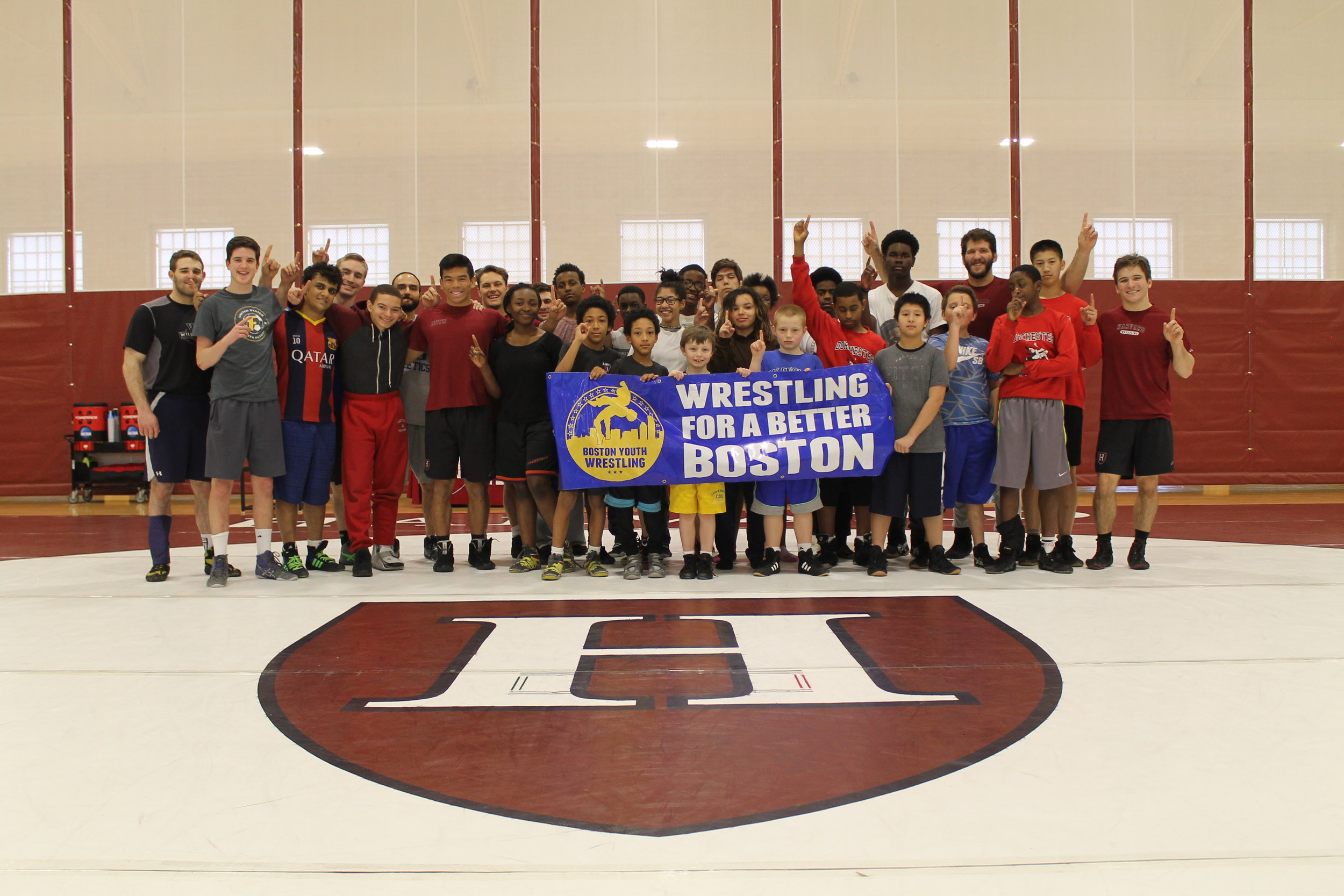 BYW student-athletes gather together alongside some of the Harvard Wrestling team's wrestlers and coaching staff for a picture at the Maklin Athletic Center in Cambridge, MA.