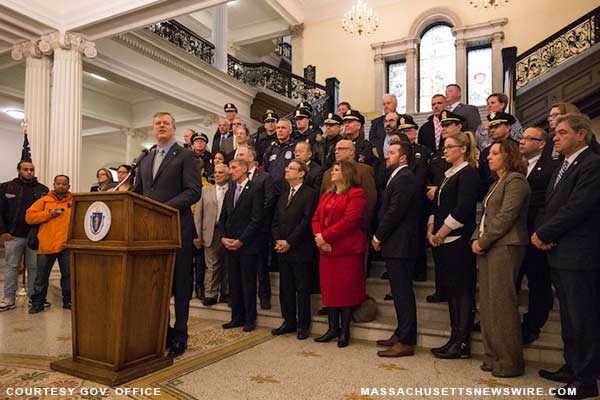 CAPTION: Governor Charlie Baker announces Shannon Grant awards during event at the Statehouse in Boston. Behind him stand legislators, local officials, members of law enforcement (including Boston Police Commissioner William Evans), and other stakeh…