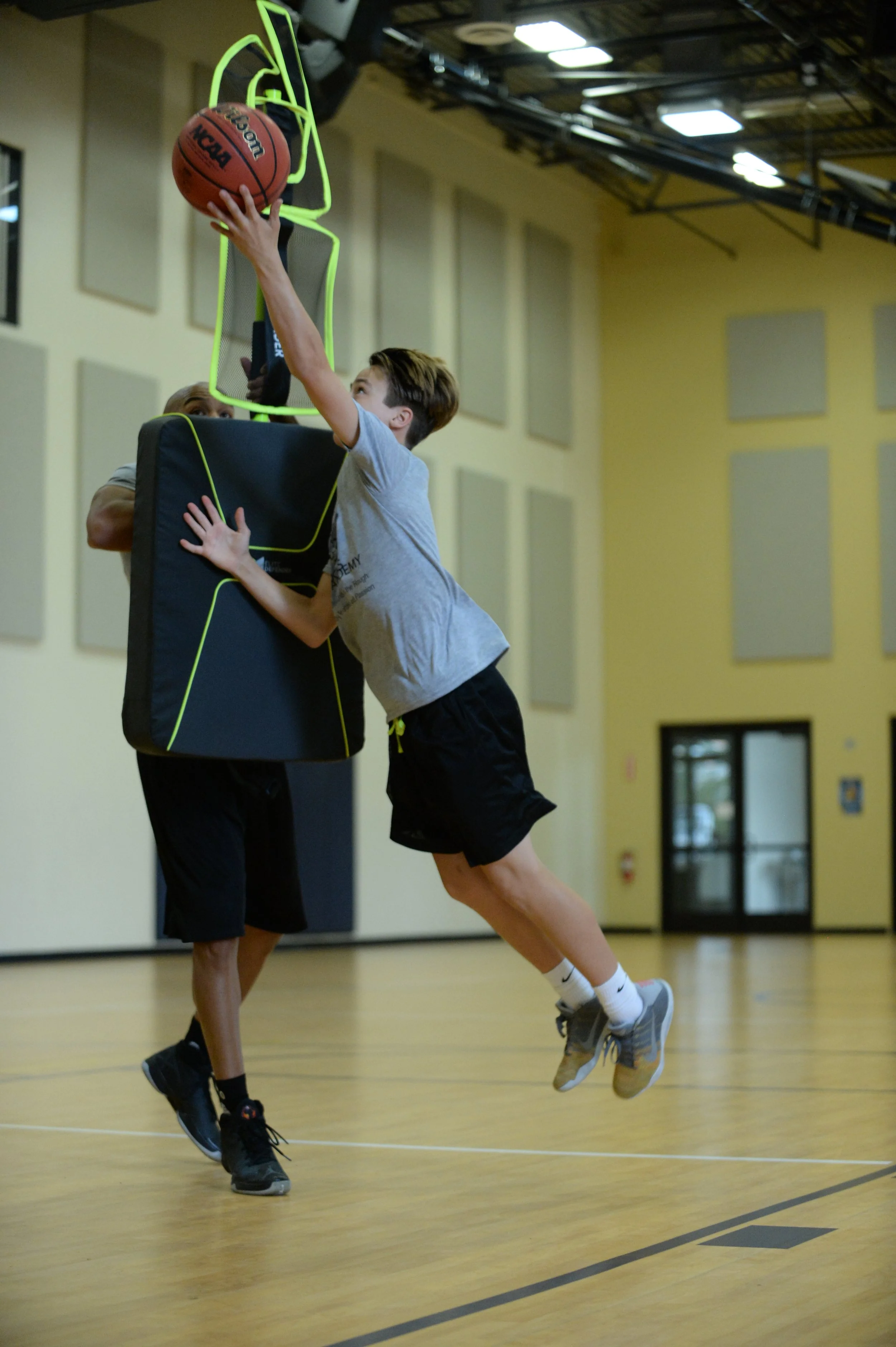 One basketball trainer using Elite Defender to train a youth basketball player on making lay-ups with contact.