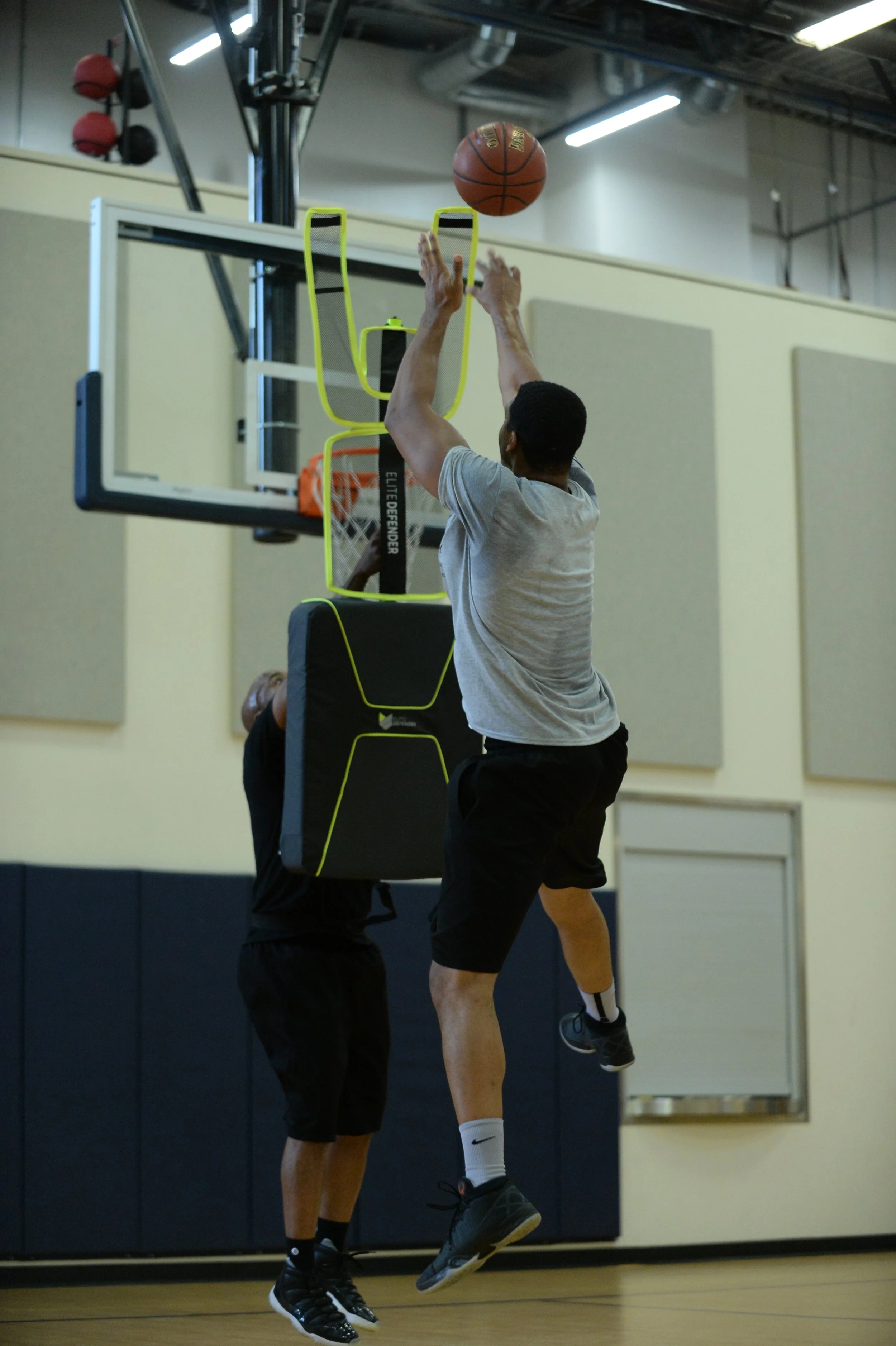 Two basketball players in a gym using Elite Defender to perform basketball training drills for shooting jump shots.