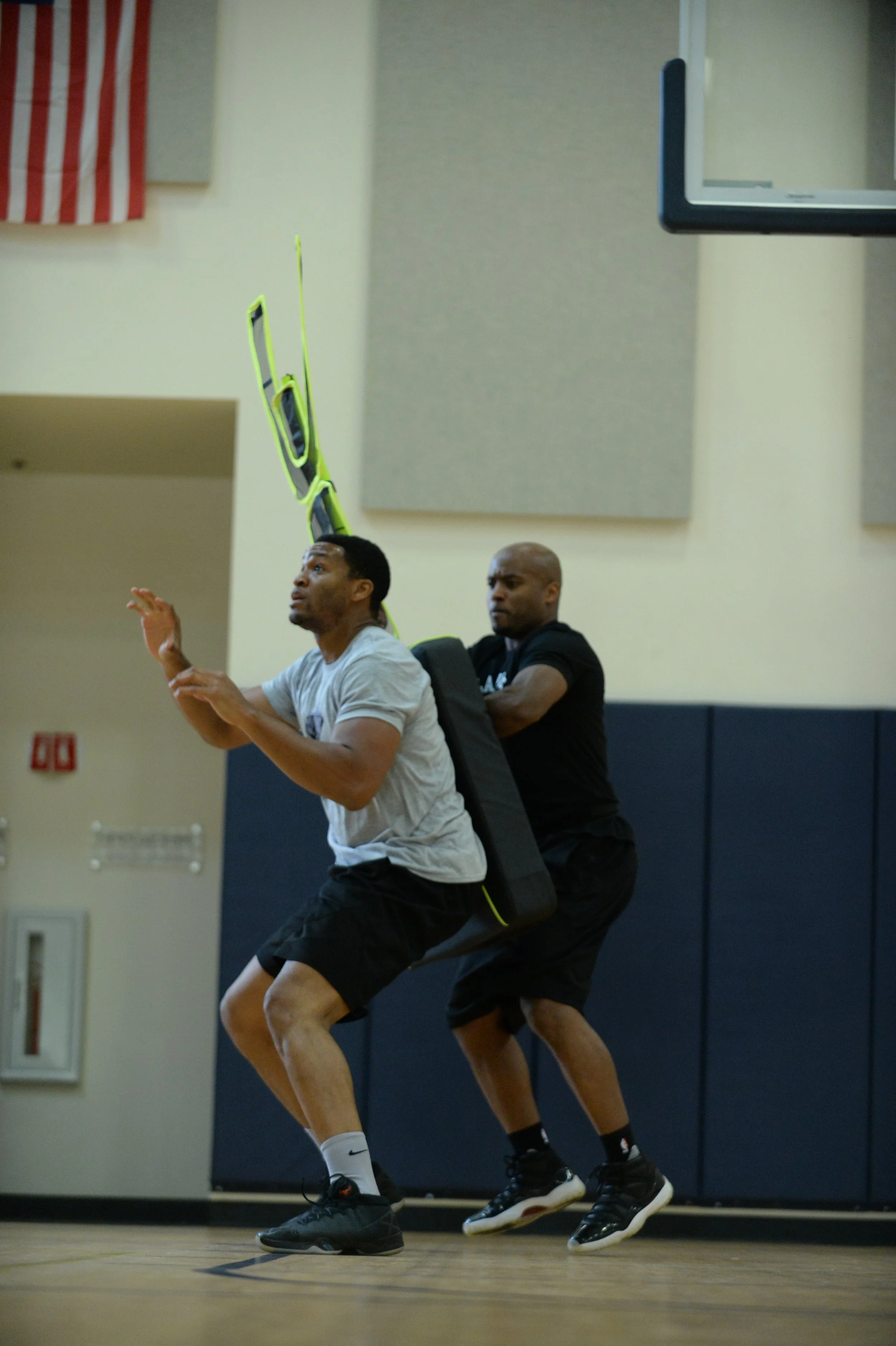 Two basketball players in a gym using Elite Defender for basketball training for rebounding the ball.