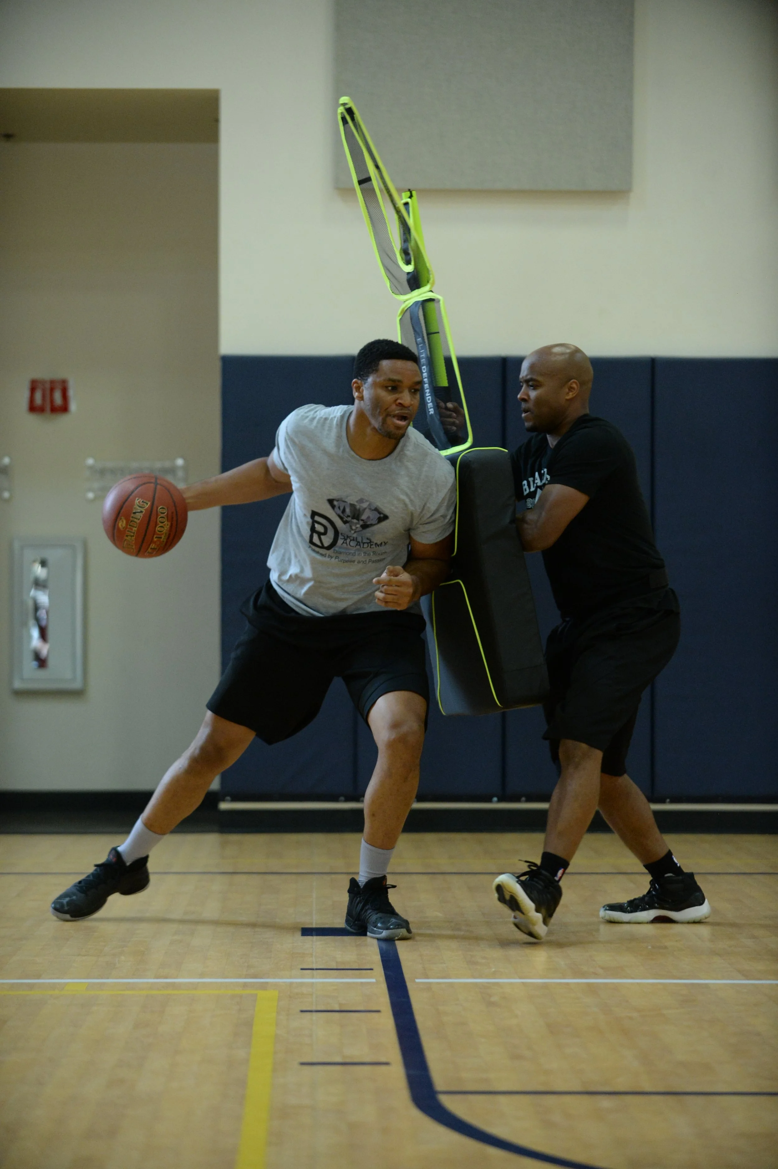 Two basketball players in a gym using Elite Defender to perform basketball training drills for dribbling and ball handling.