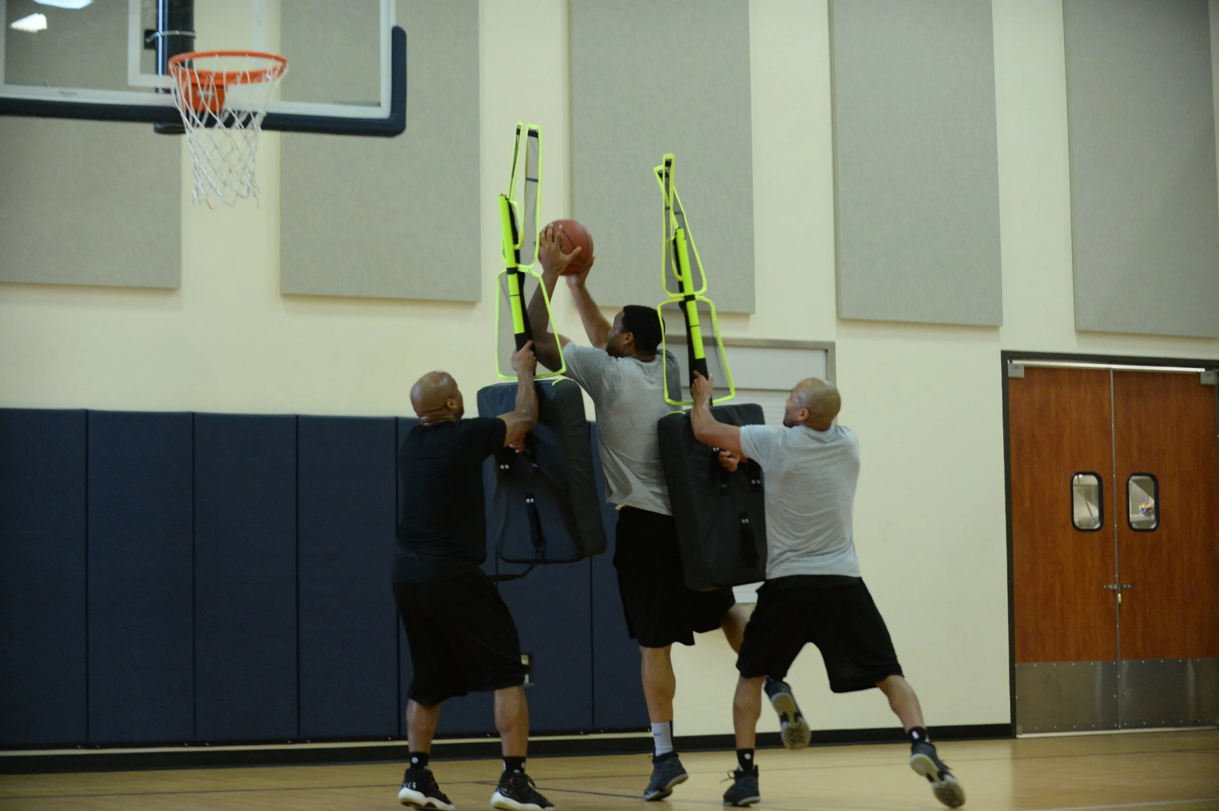 Three players demonstrating how multiple Elite Defenders can be used for basket ball training for lay-ups.