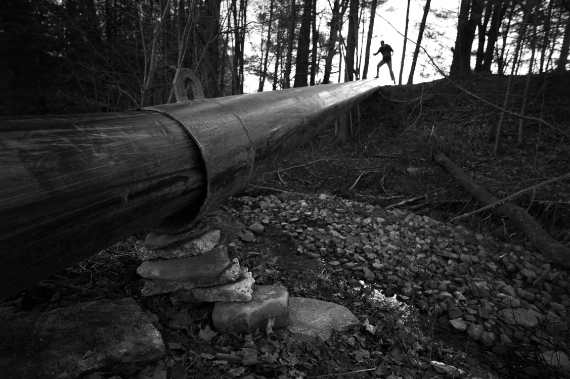 An activist walks a water pipe stretched precariously across the landscape in Bradford County, one of the areas most heavily impacted by shale gas extraction. © Lynn Johnson/MSDP 2012