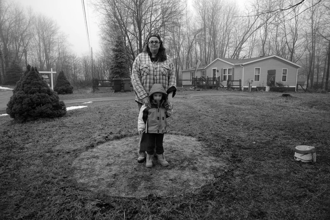 McEvoy and her daughter stand in the brown spot that used to hold their water buffalo, the only source of safe drinking water for the family. The container, originally provided by Rex Energy, was taken away when their water was deemed "safe", though it was still brown and smelled like rotten eggs as it flowed from the kitchen faucet. © Lynn Johnson/MSDP 2012