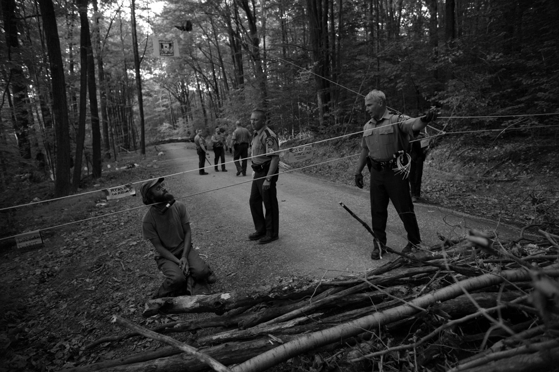  One of many activists who shut down a large drilling operation in Moshannon State Forest sits behind a barricade of brush, locked to a rope. The activists held off police efforts to open the road to the rig, which forced its shutdown for an entire d
