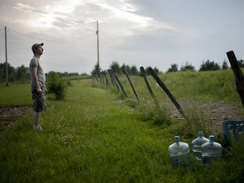 Jason Lamphere looks out over his property. He and his family have been without well water since 2010 after methane migrated into their system. A garden plot behind him lays unplanted since he lacks clean water to irrigate it. He believes nearby gas drilling and fracking caused the problem. Monroeton, Bradford County, 2011. © Nina Berman/MSDP 2011