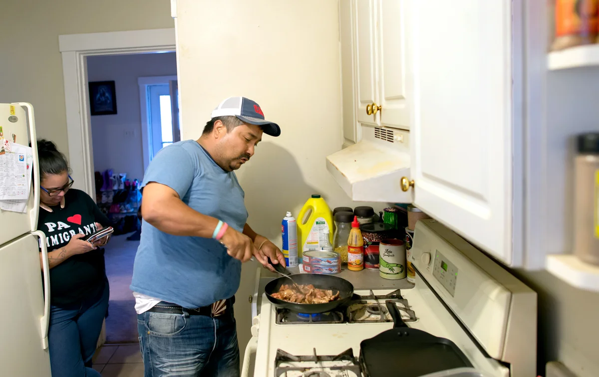 Adriana Quinones, a friend of the family, checks her smartphone while Jose prepares fajitas. © Nate Guidry/TDW 2017