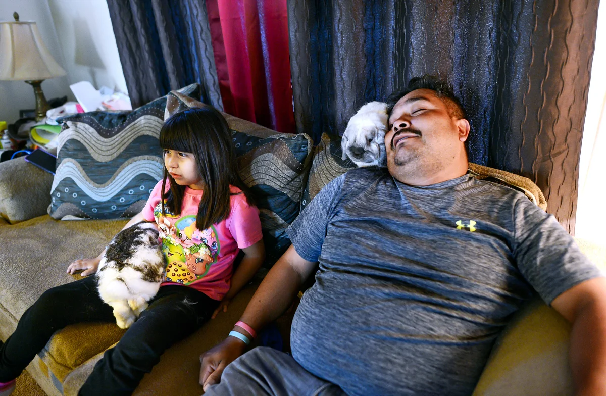 Briana and Jose with their pet rabbits, while watching television. © Nate Guidry/TDW 2017