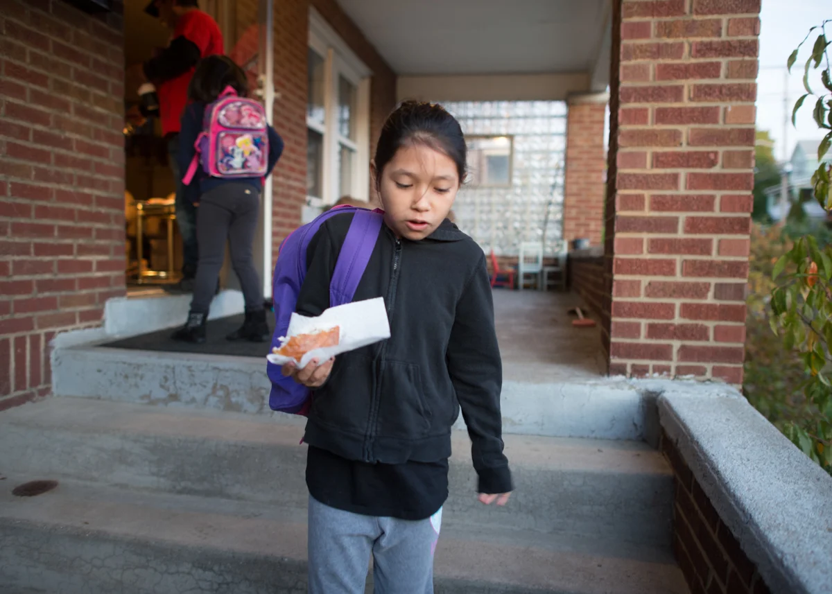 Emma finishes her breakfast, while walking down the steps to go to school. © Nate Guidry/TDW 2017