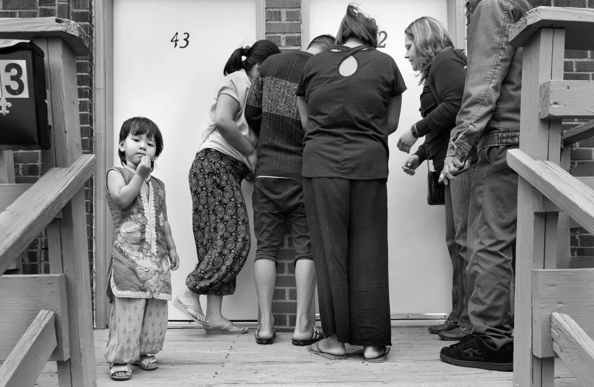 The day after their arrival, the family are given a key to their new apartment in the Brentwood neighborhood of Pittsburgh. Here, they are learning how to use a key in a lock for the first time. Previously, they lived in the Beldangi refugee camp, Damak, where there are no locks on the doors. © Scott Goldsmith/TDW 2017
