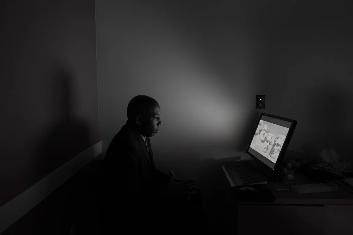 October 25, 2017 USCIS Office in Penn Center, Monroeville, PA Mark Phillips, a staff member of the U.S. Citizenship and Immigration Services, sits at a monitor in the room where new citizens are viewing the same “Welcome to America” video. Images of our icons and history float over the screen showing how the strength of our nation has always been in the diversity of its citizens. © Lynn Johnson/TDW 2017