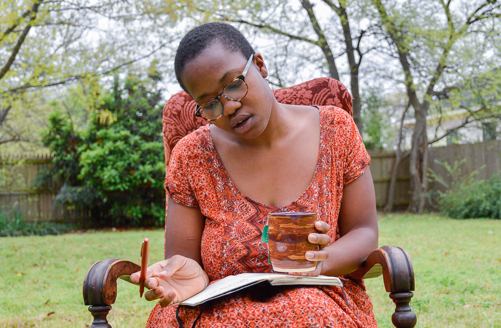  Loré Yessuff, as she shits outside, writing in a journal. 