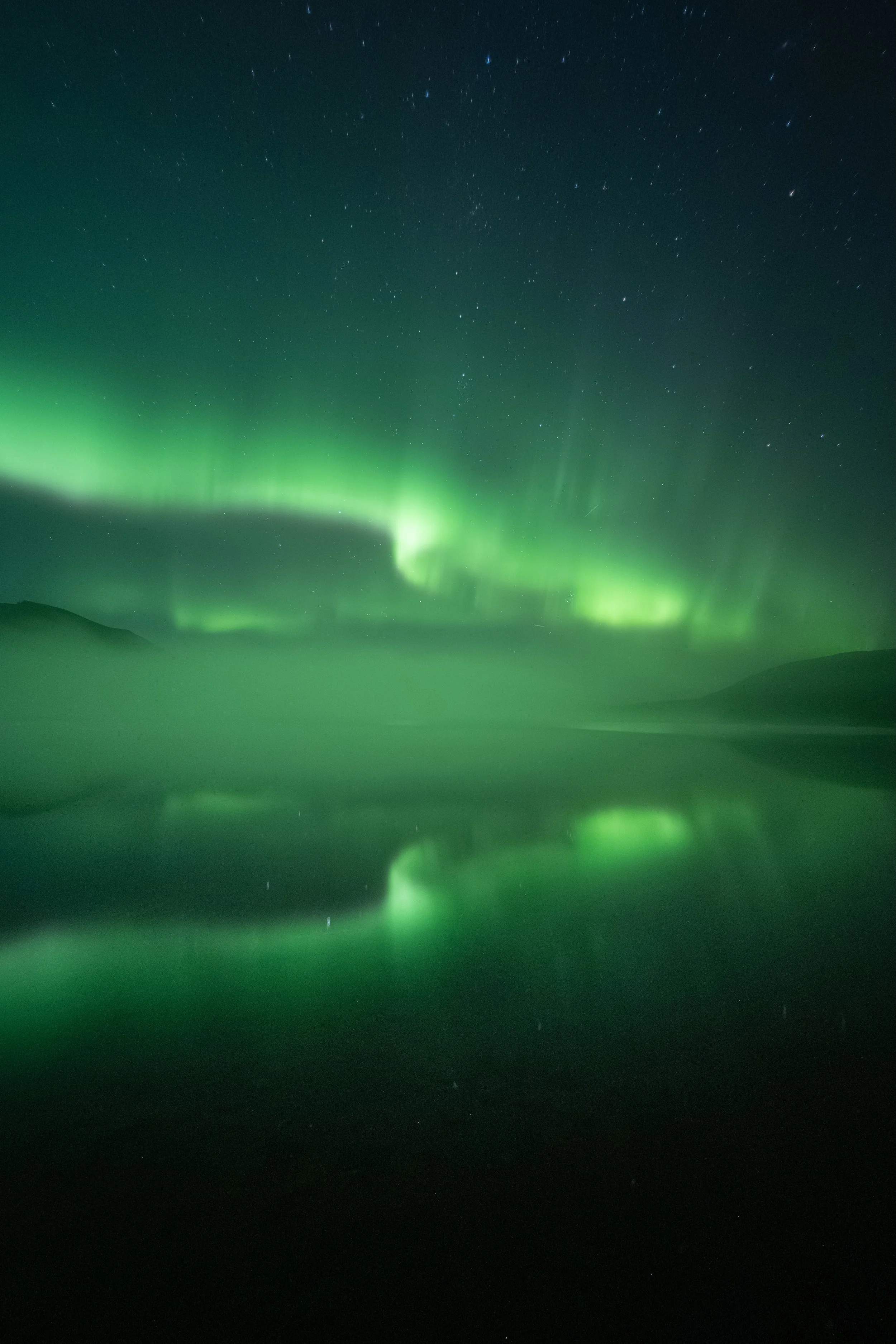 Vibrant northern lights dancing over Laslui Lake at Spatsizi Lodge in Spatsizi Plateau Wilderness Provincial Park, in Northern British Columbia.