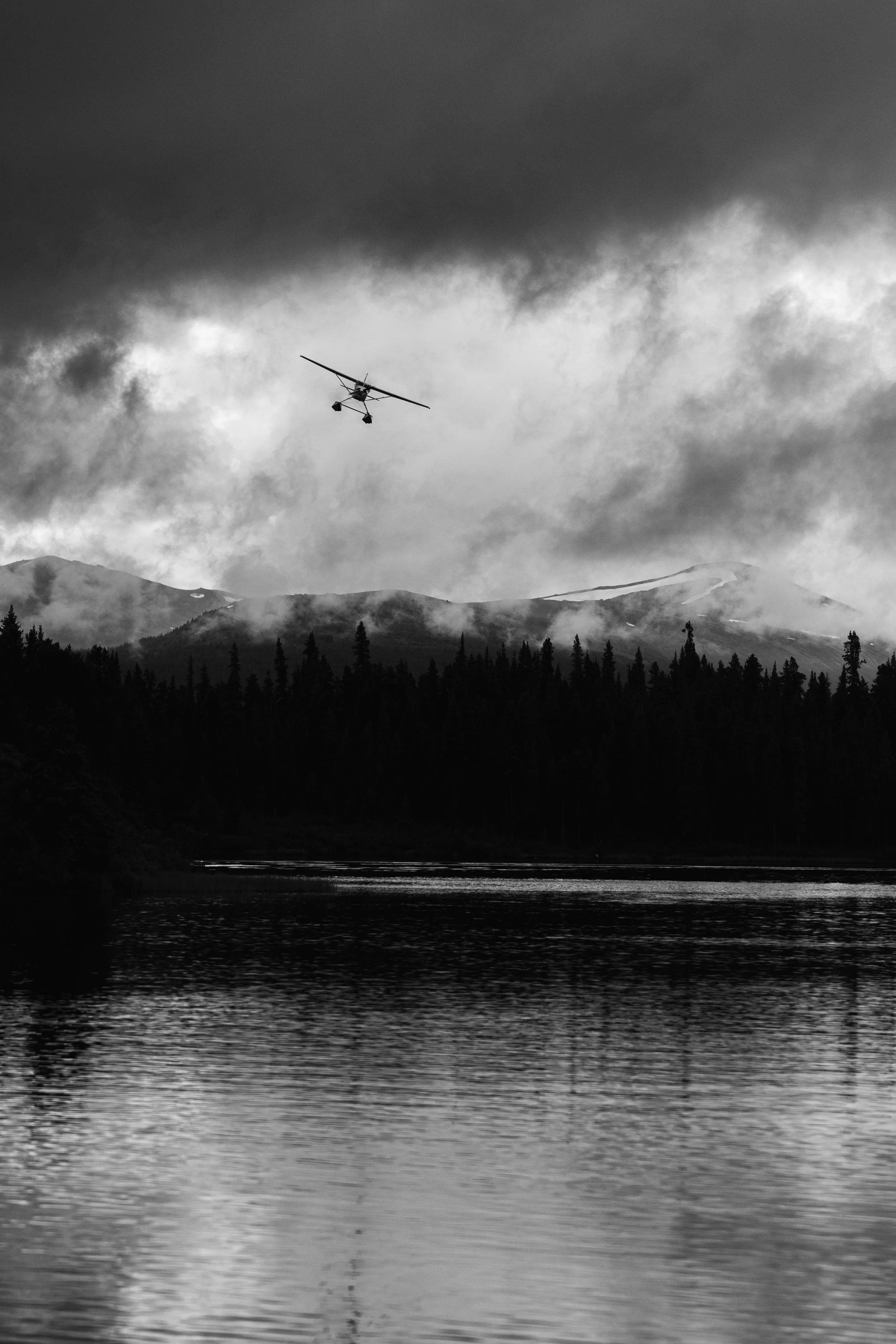 Black and white photograph of a cessna 185 float plane coming in to land on Tatlatui Lake, within Tatlatui Provincial Park in Northern British Columbia