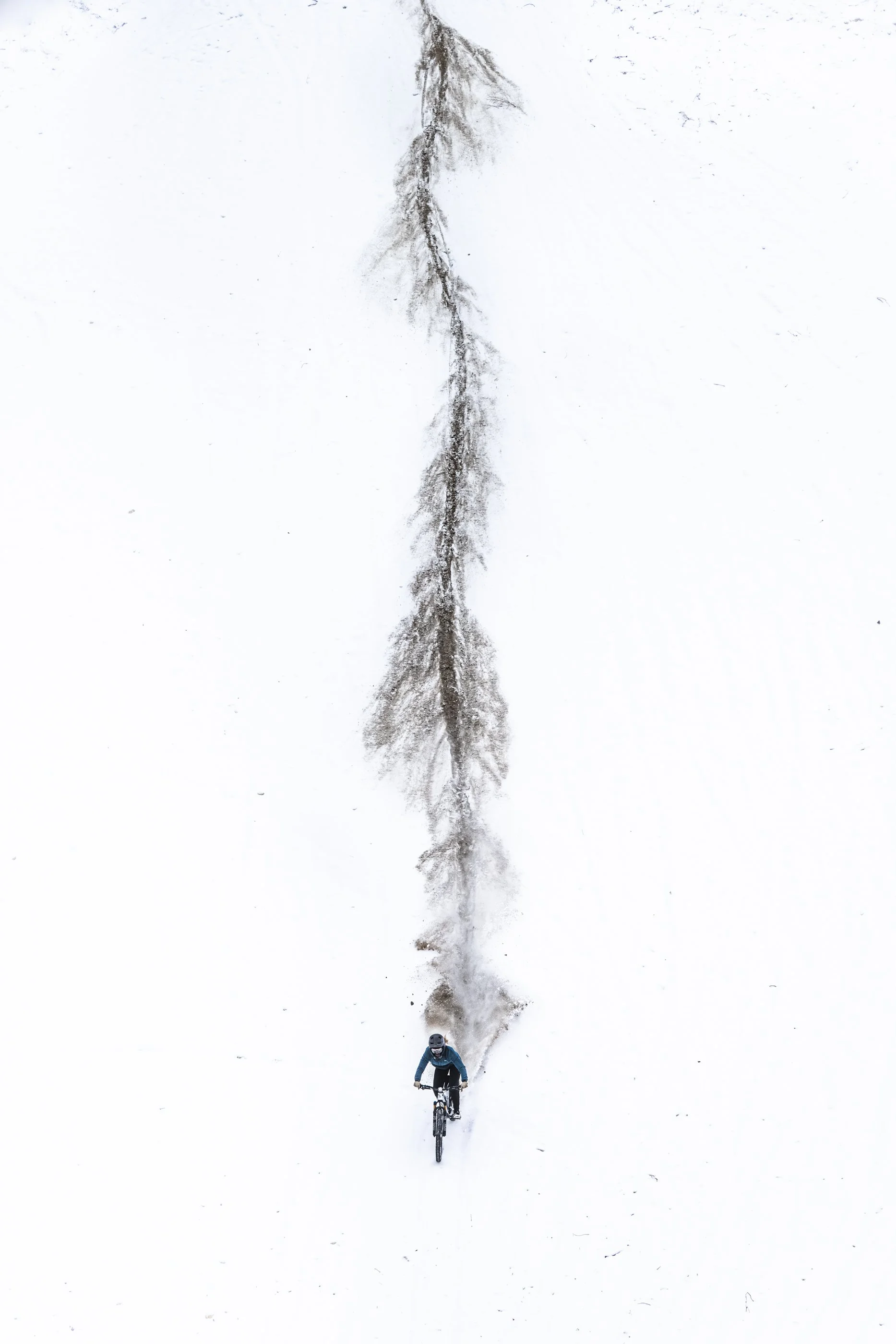 Freeride mountain biking through a snowy canvas, professional athlete Kirsten VanHorne rides down a hillside near Castlegar, British Columbia. 
