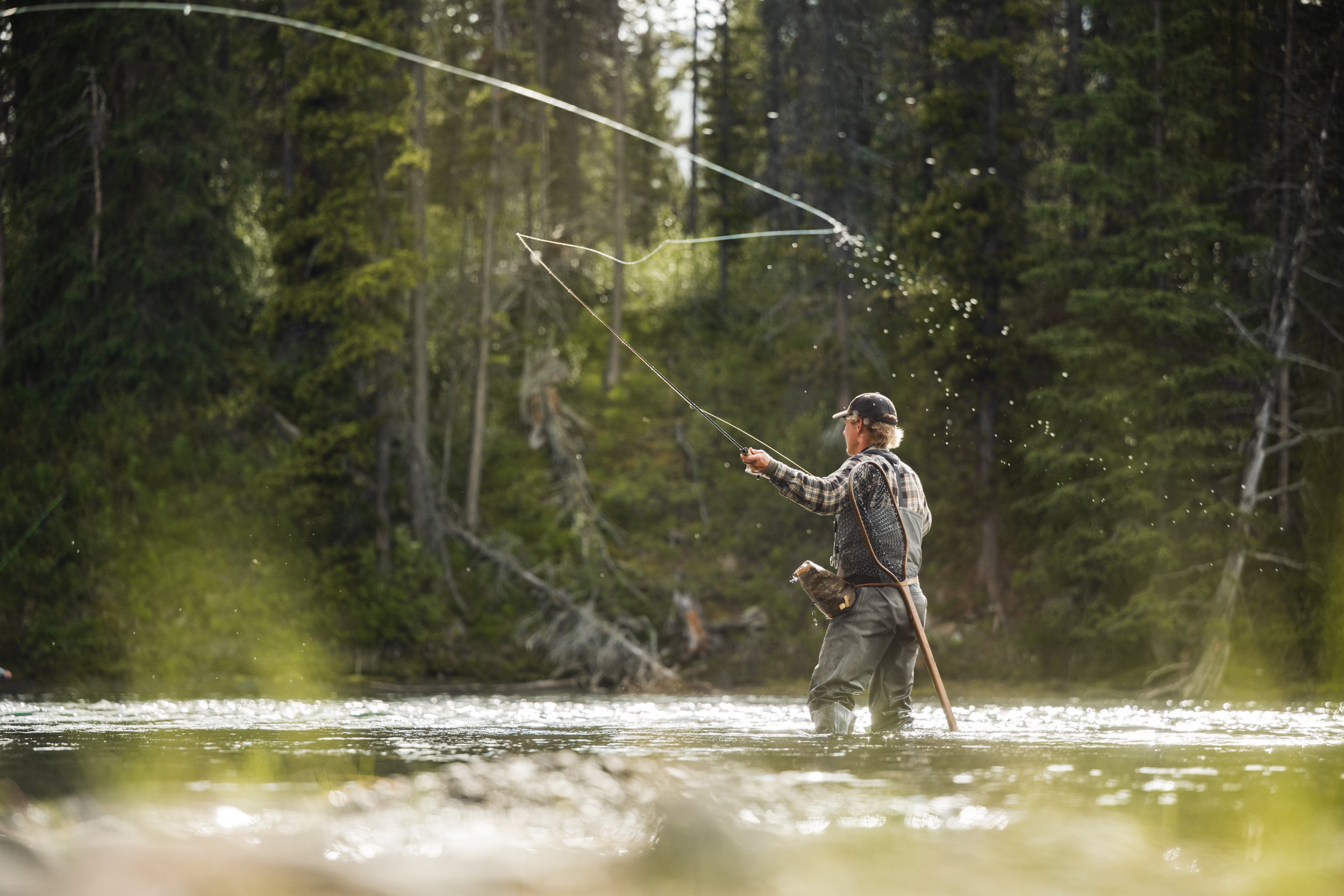 A fisherman casts out his line into the outflow of Tatlatui Lake, within the remote wilderness of Tatlatui Provincial Park in Northwest British Columbia, Canada on a summer day