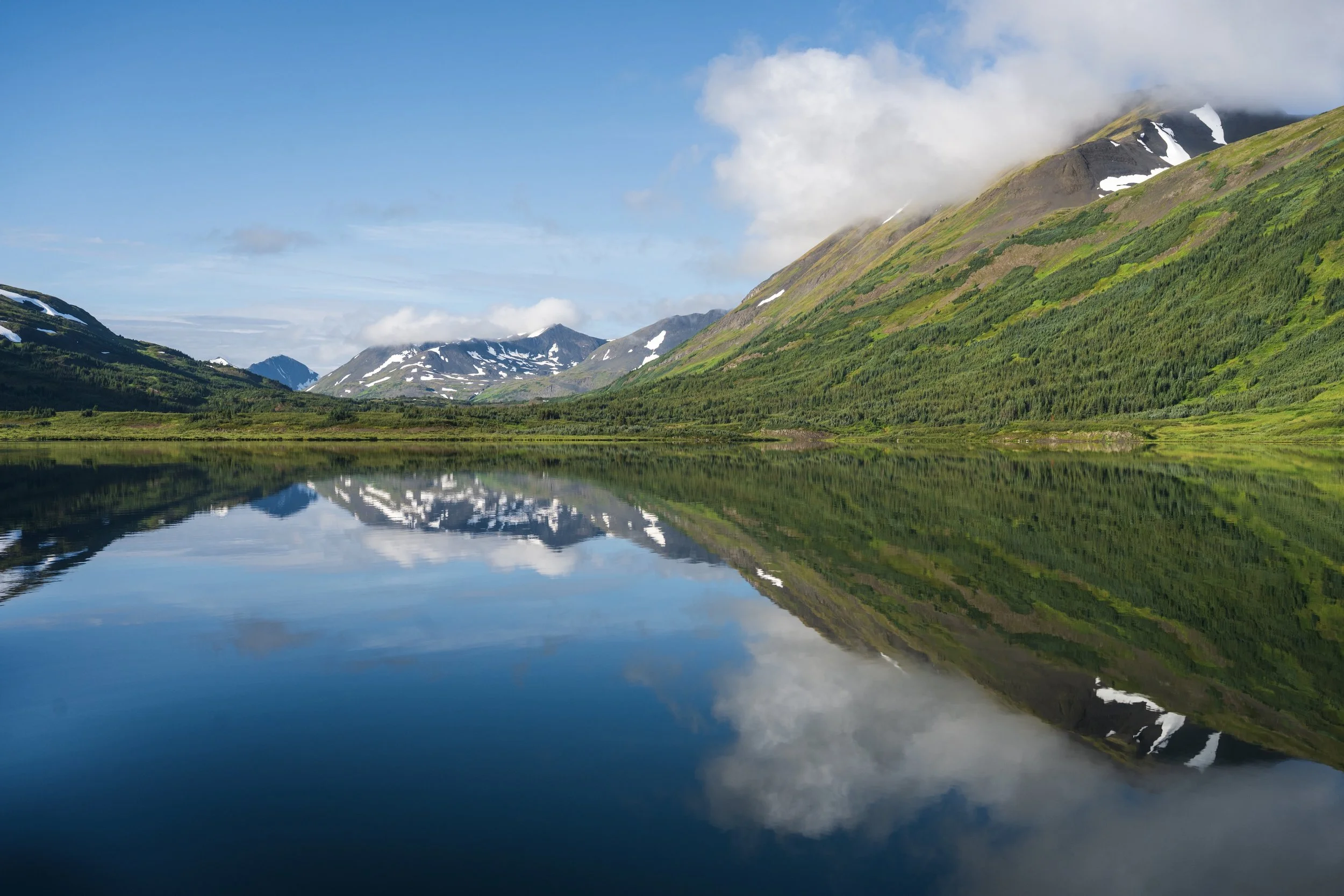 A clear blue day and the reflections on Ella Lake, a remote body of water within Spatsizi Plateau Provincial Park, British Columbia