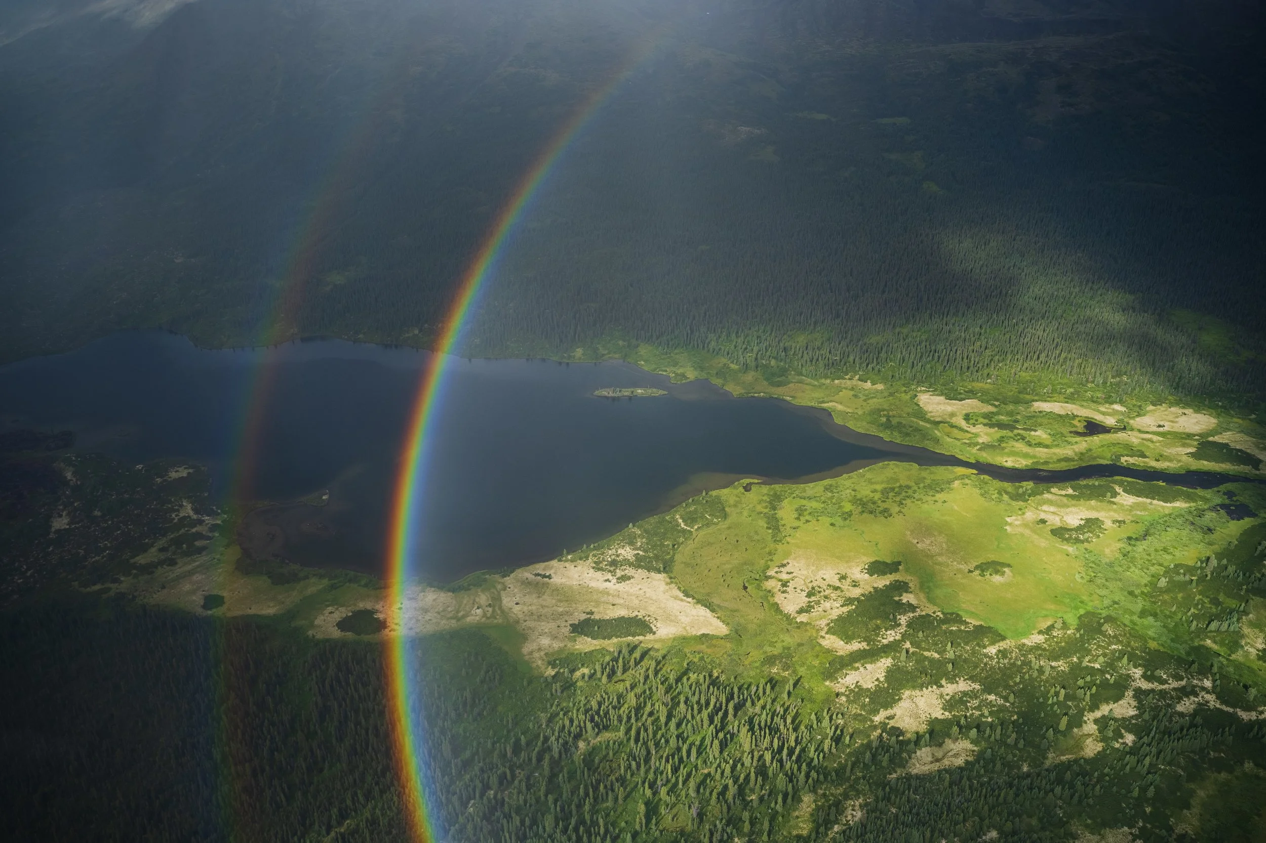 An aerial perspective of a rainbow over the outflow of Stalk Lakes, in Tatlatui Provincial Park within Northern British Columbia.