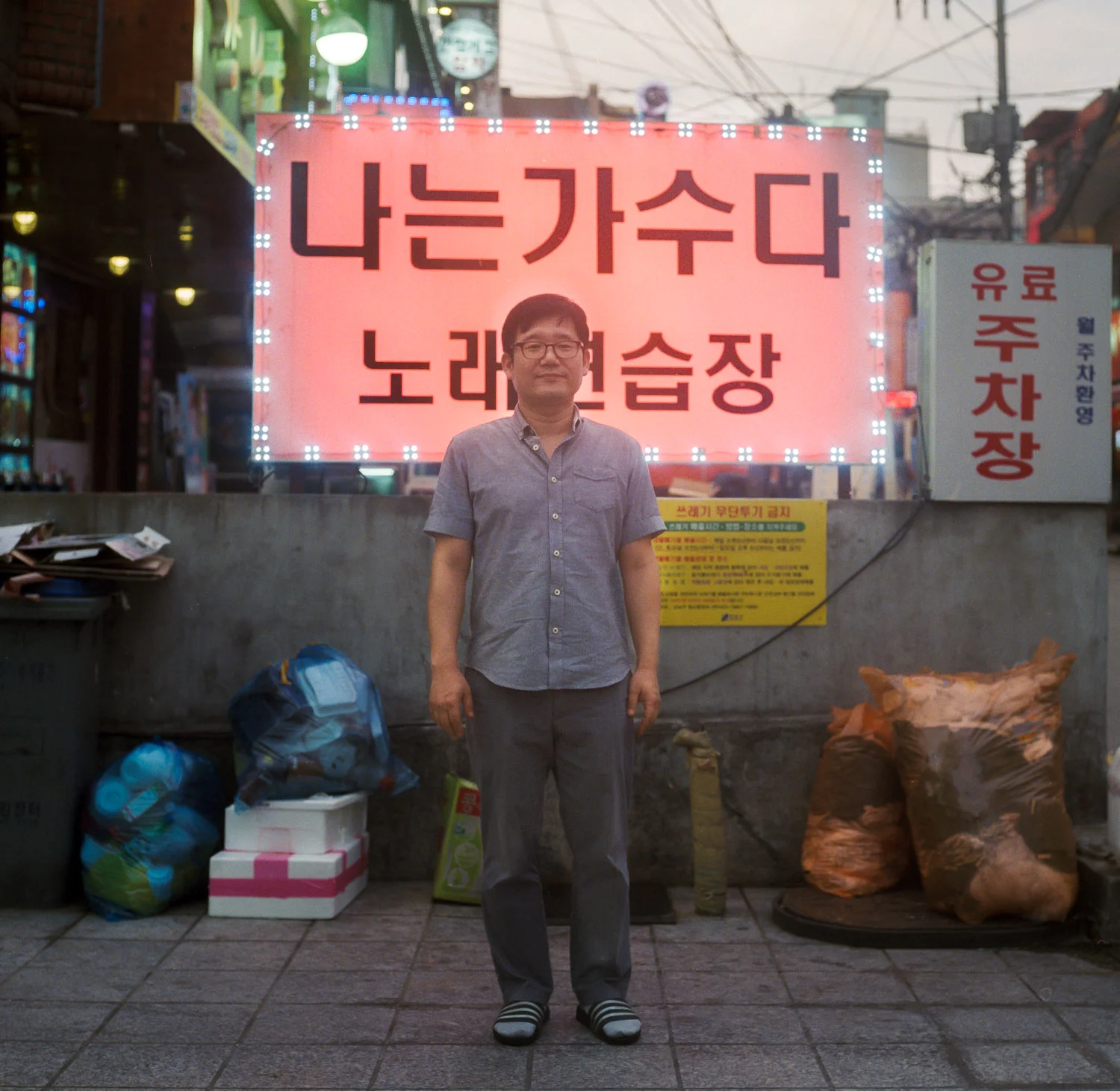 " I want to be singer " . An entertainment game room owner standing in front of a Karaoke Room advertising in Gangnam district / Seoul