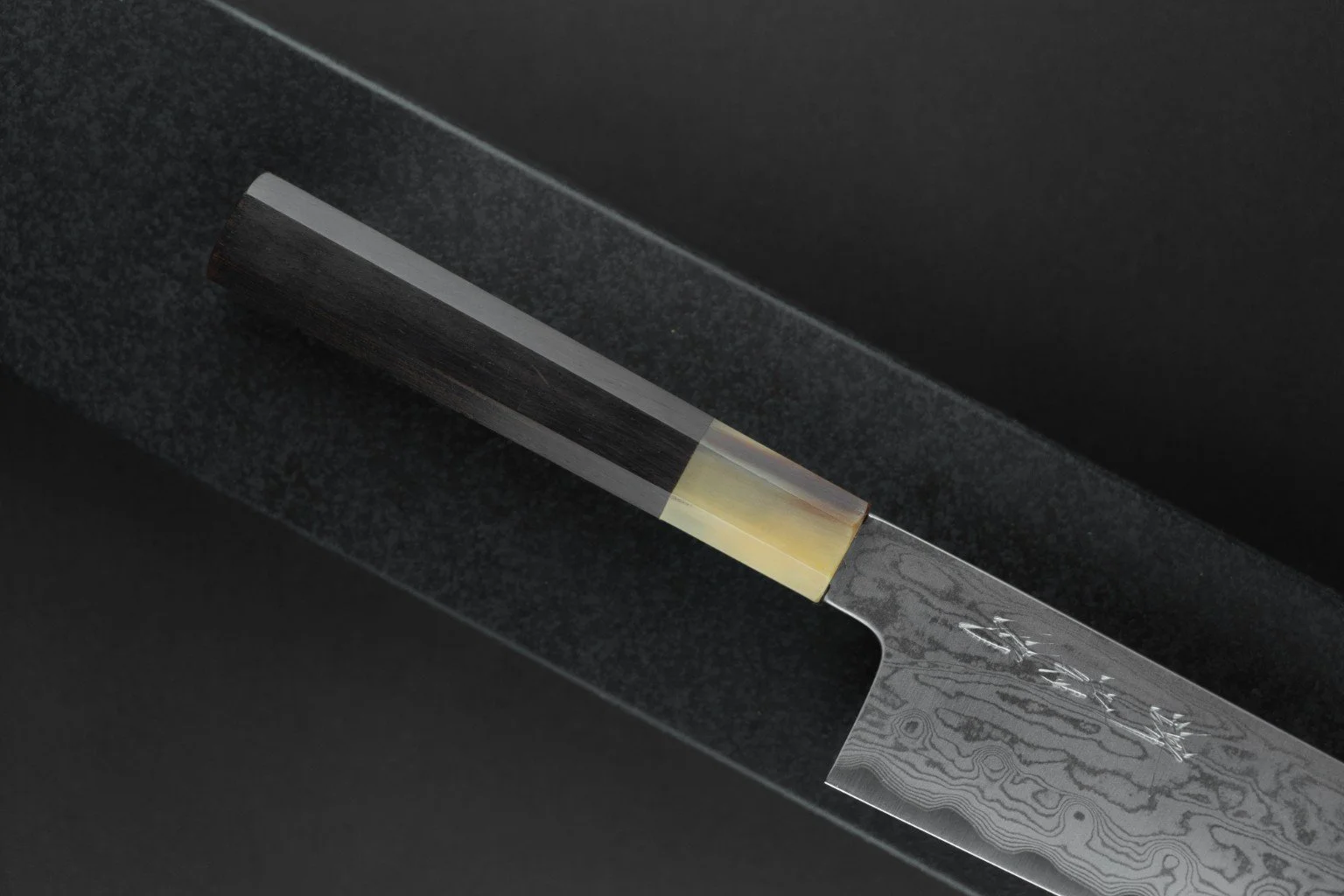 Détail du manche octogonal en ébène et corne de buffle blonde du Tokuseï Kikumori Suminagashi Santoku 165 mm.