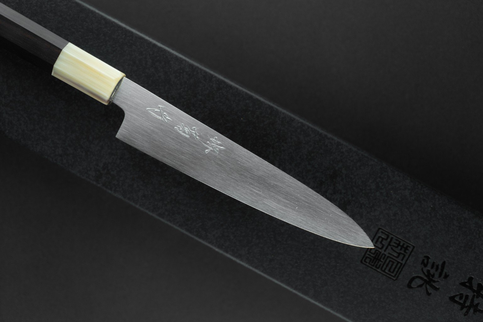 Détail de la lame à l’aspect satiné et de la gravure du Tokuseï Kikumori Suminagashi Petty 135 mm.