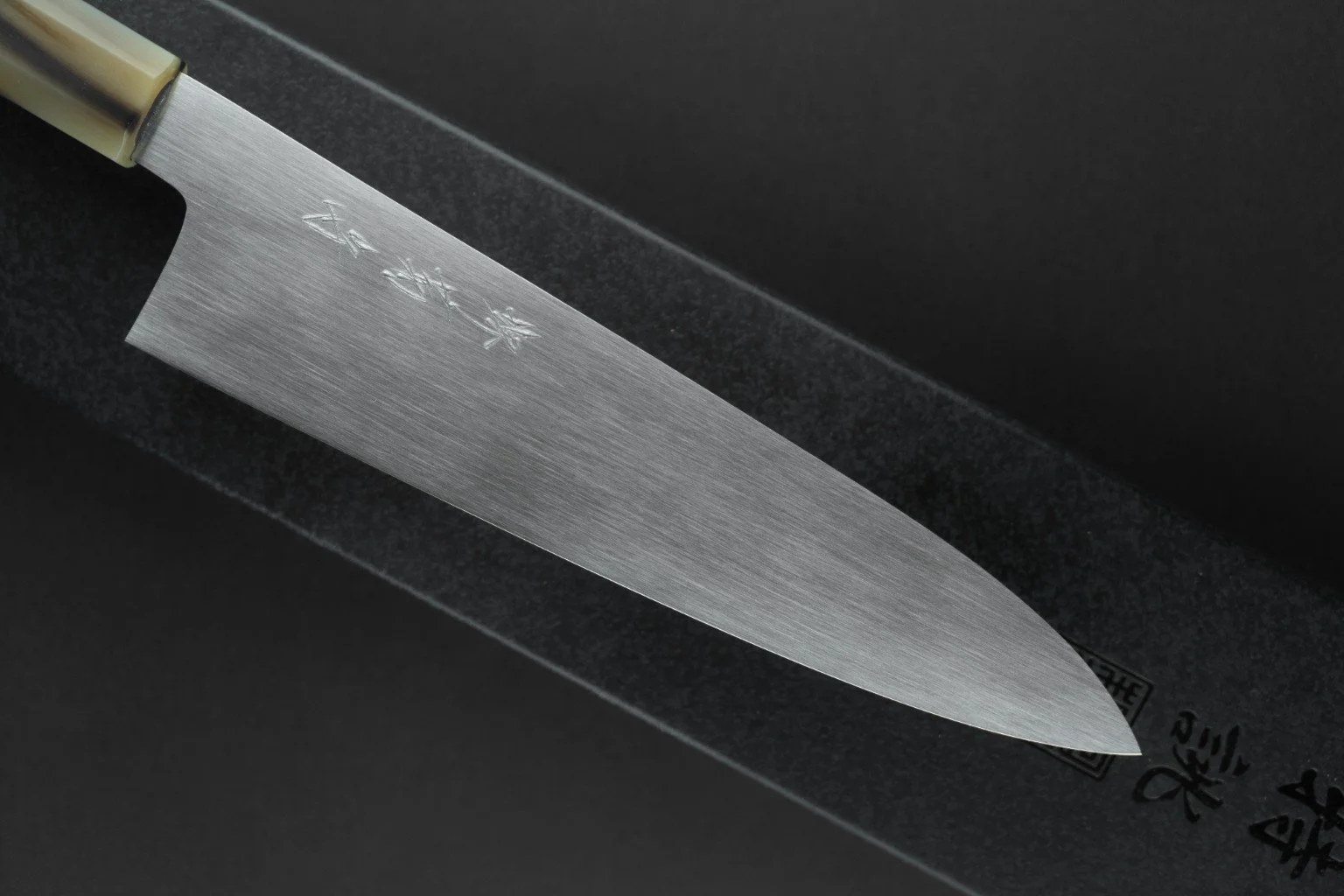 Détail de la lame à l’aspect satiné et de la gravure du Tokuseï Kikumori Suminagashi Gyuto 210 mm.