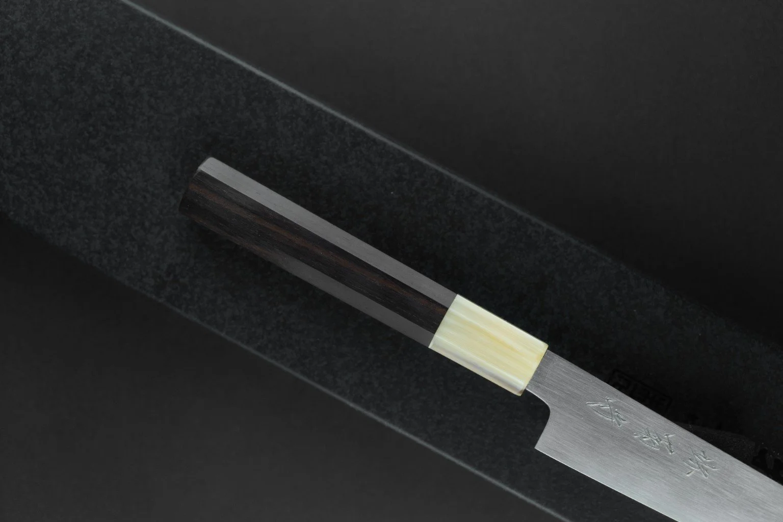 Détail du manche octogonal en ébène et corne de buffle blonde du Tokuseï Kikumori Suminagashi Petty 135 mm.