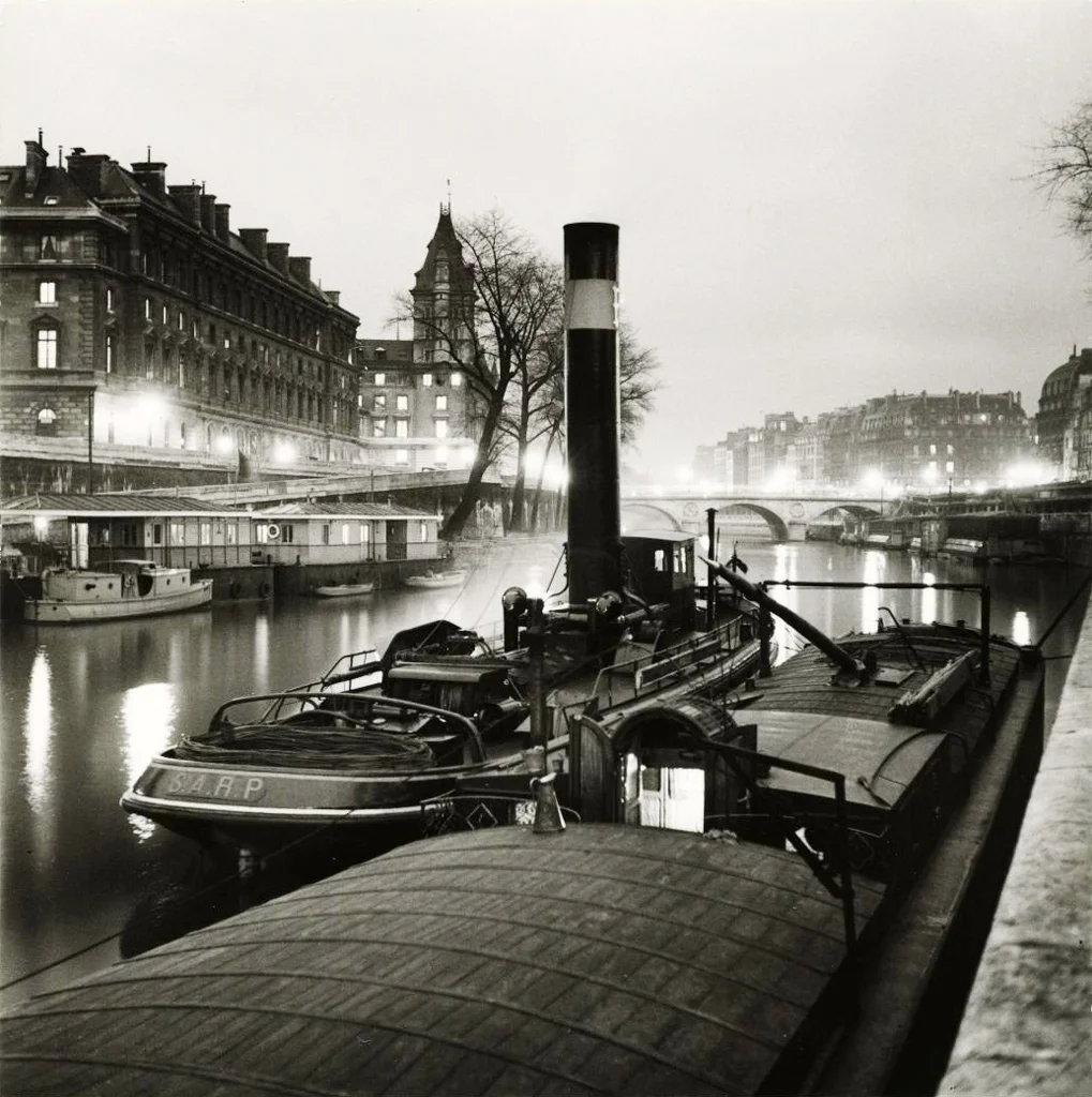 Roger Schall, Remorqueur et péniches amarrés sur le quai de Gesvres, devant l'île de la Cité, vue sur la tour de l'horloge et sur le pont au Change, 1er arrondissement, Paris. 1936. Source: Lien
