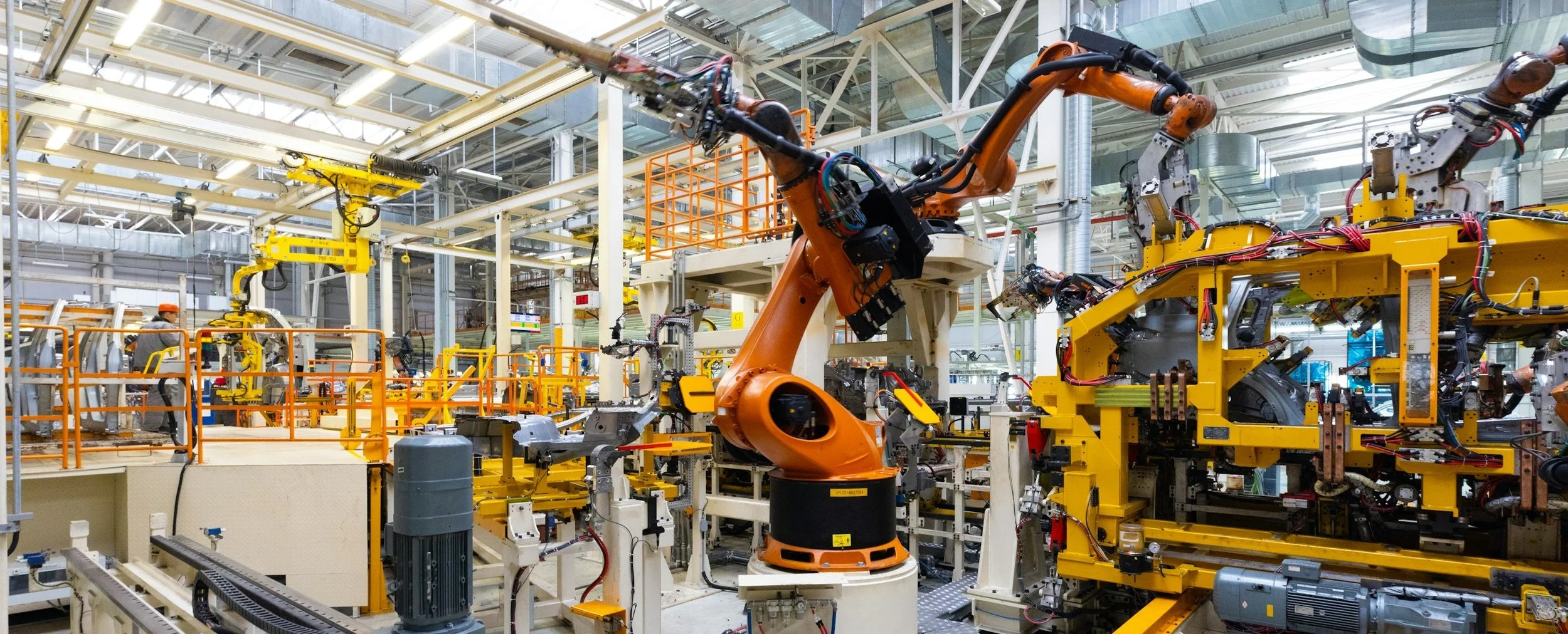 An industrial factory with robotic arms and machinery manufacturing automotive parts.