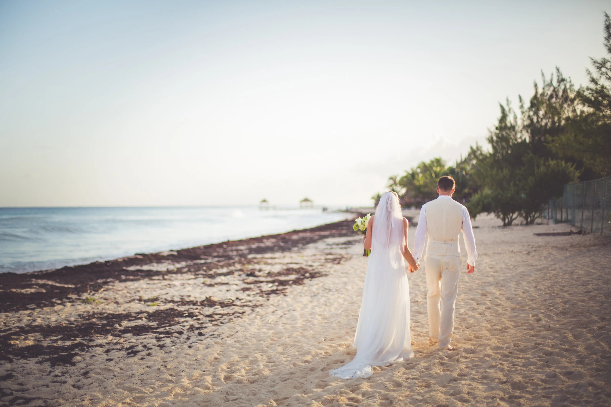 bride and groom walk beach at sunset in mayan riviera mexico
