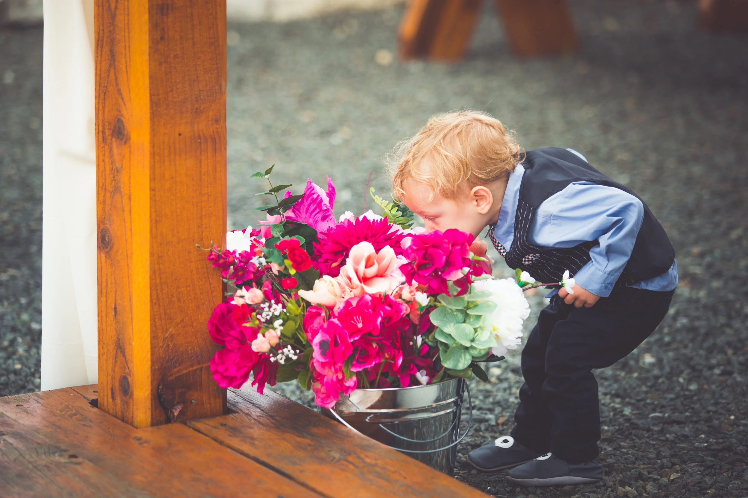 young boy smells wedding flowers