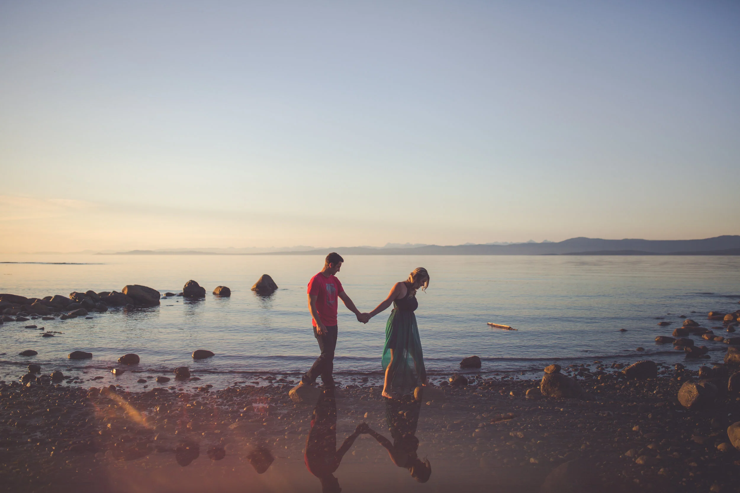 couple walks on beach at sunset in Qualicum Beach