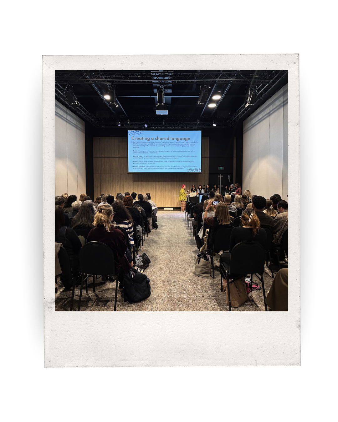 a room of people listening to a workshop presented by young people