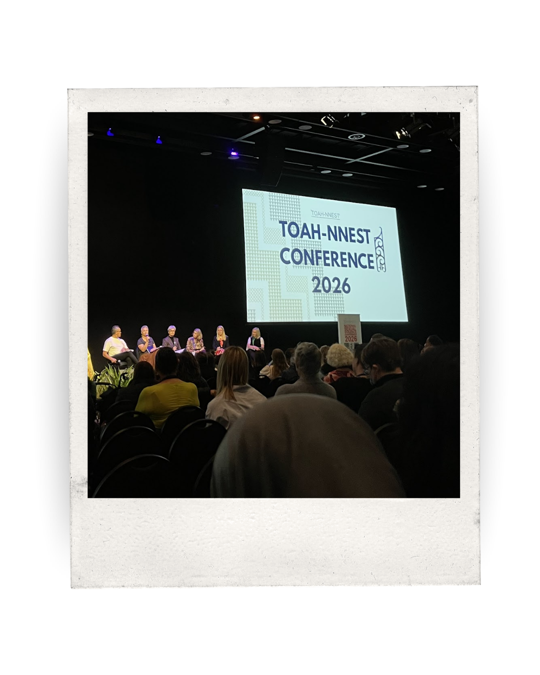 a conference stage with  panel of speakers