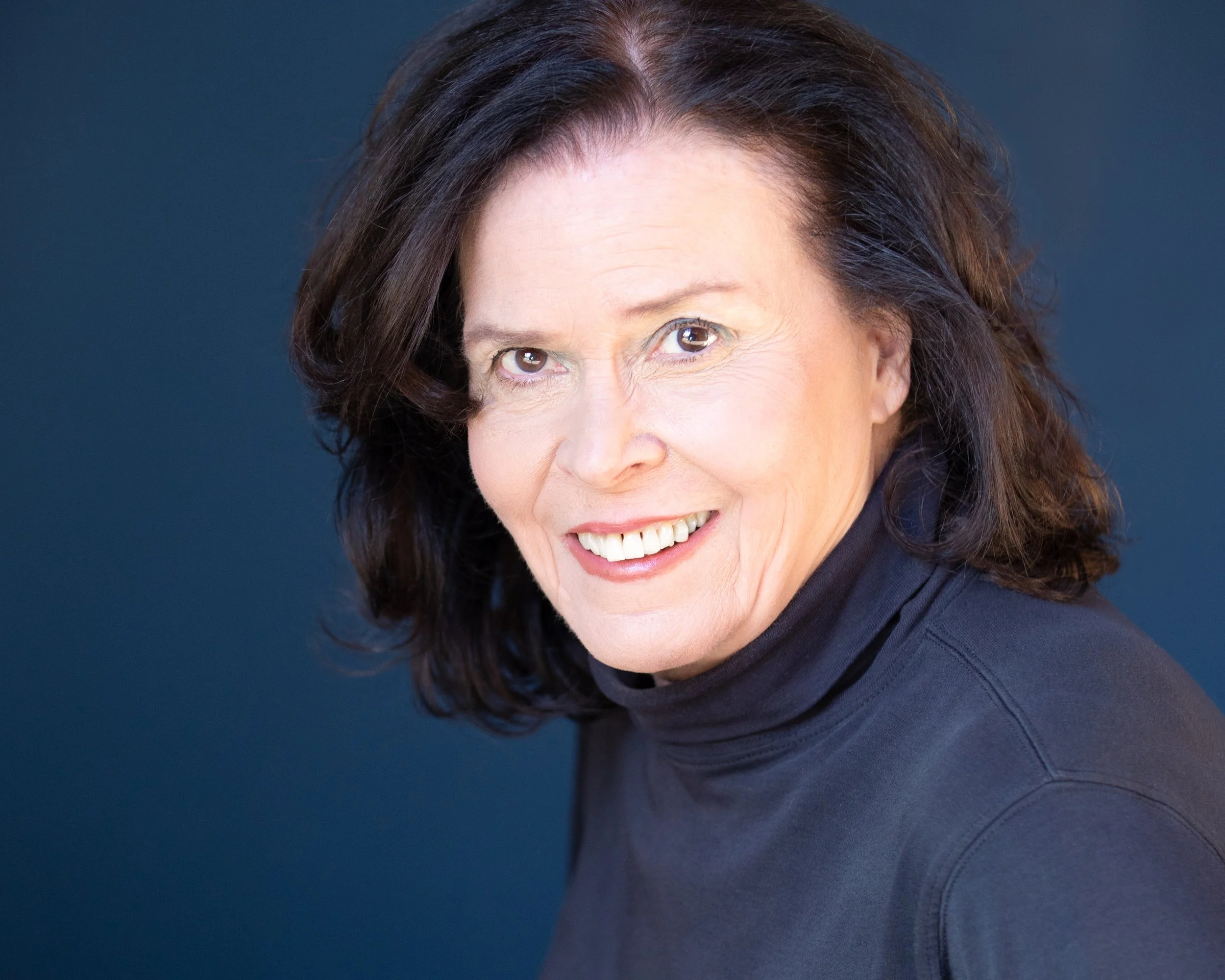 an older woman's professional headshot against a solid blue background