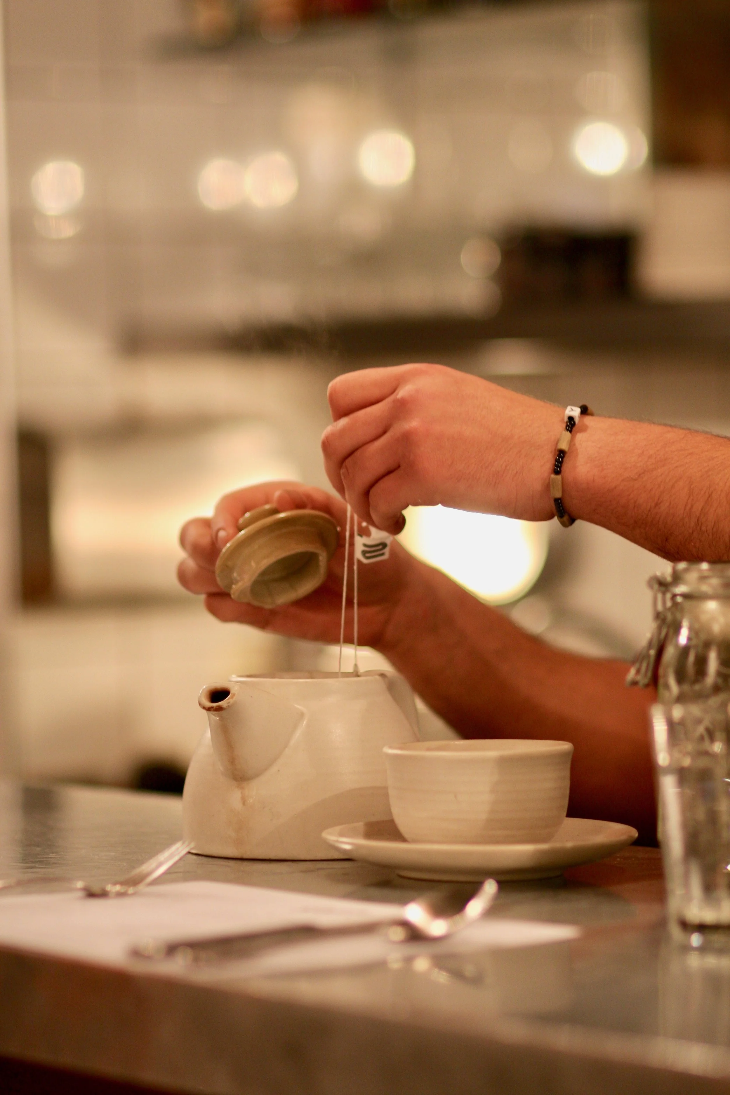A person dipping a teabag into a pot of tea