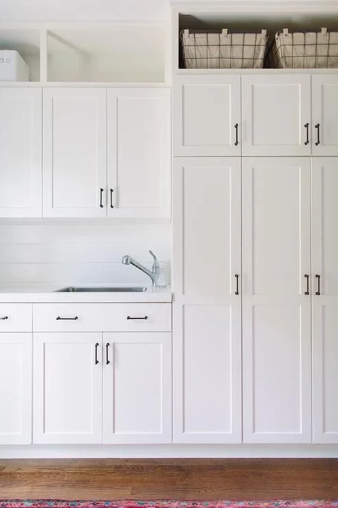 White shaker cabinet fronts with bronze hardware. Take storage to the ceiling to maximize space and free-up work surfaces.