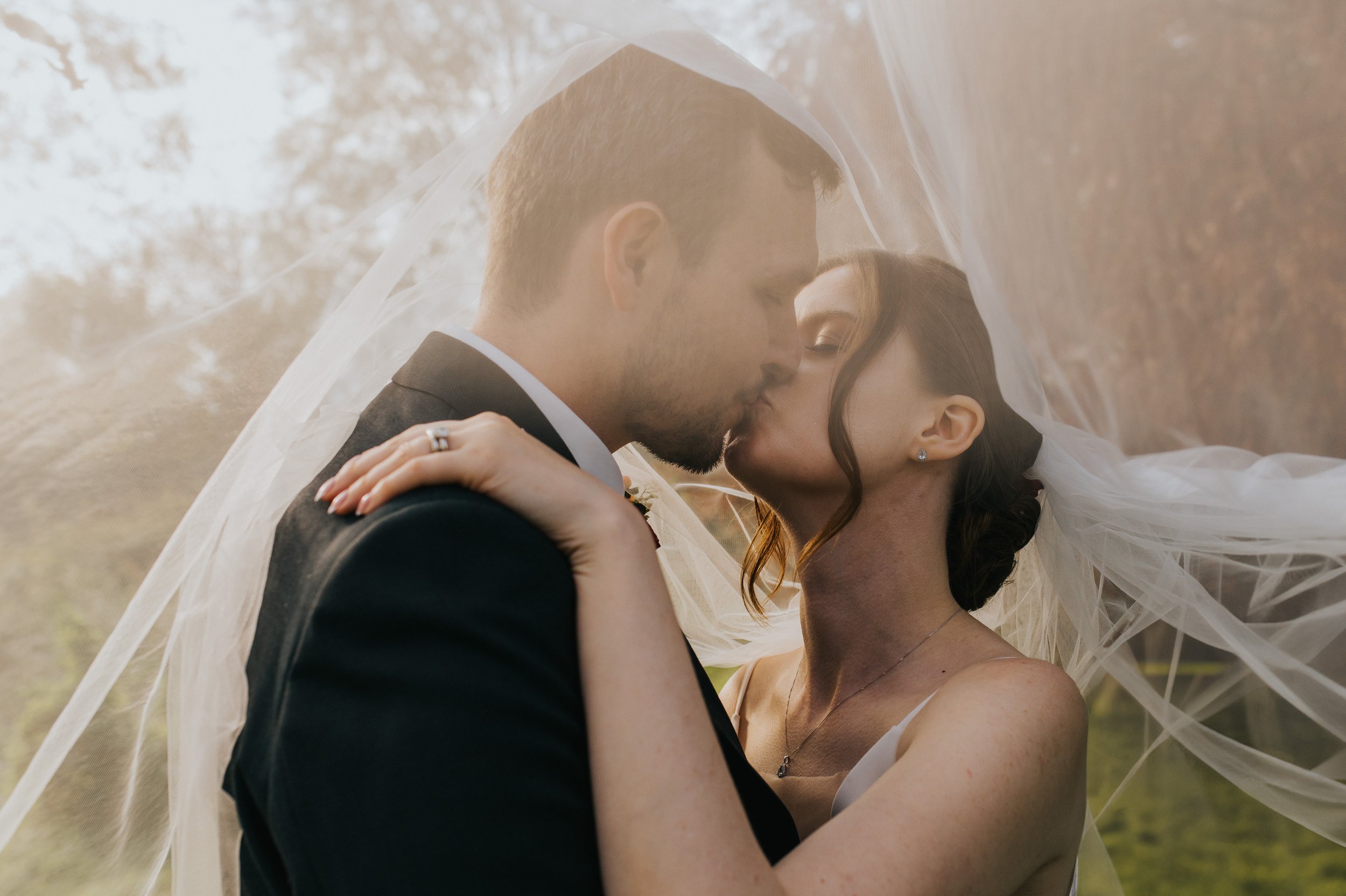 Bride & Groom under the veil kissing.