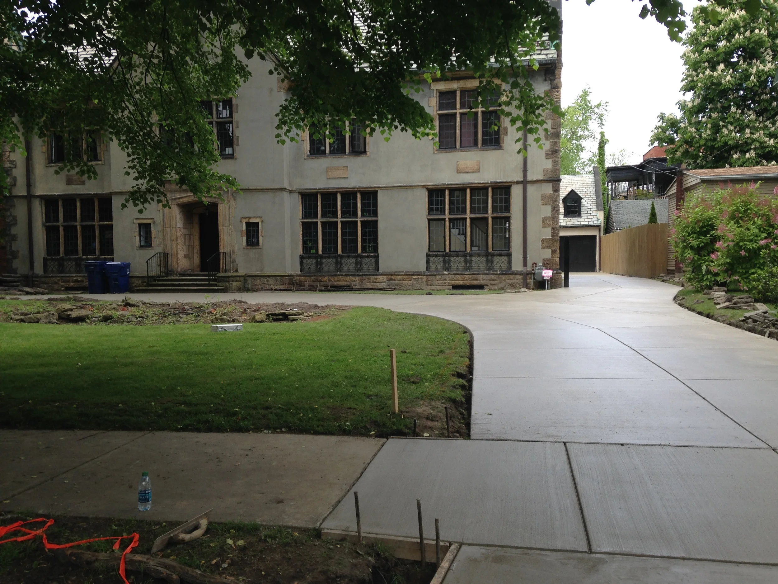 A cement wrap-around driveway in front of a large house. The cement is setting.