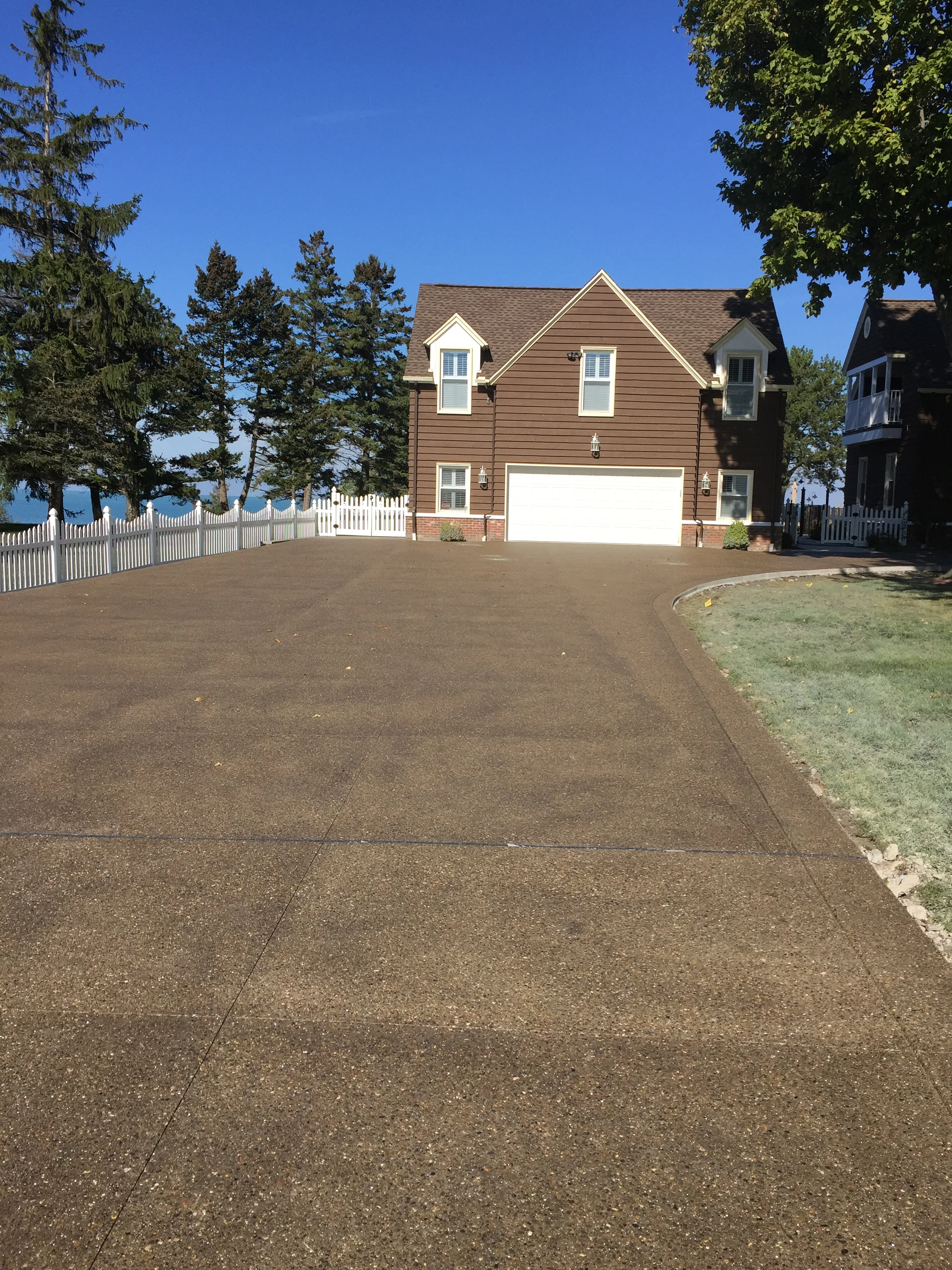 A wide, darker colored concrete driveway leading up to a brown two-car garage.