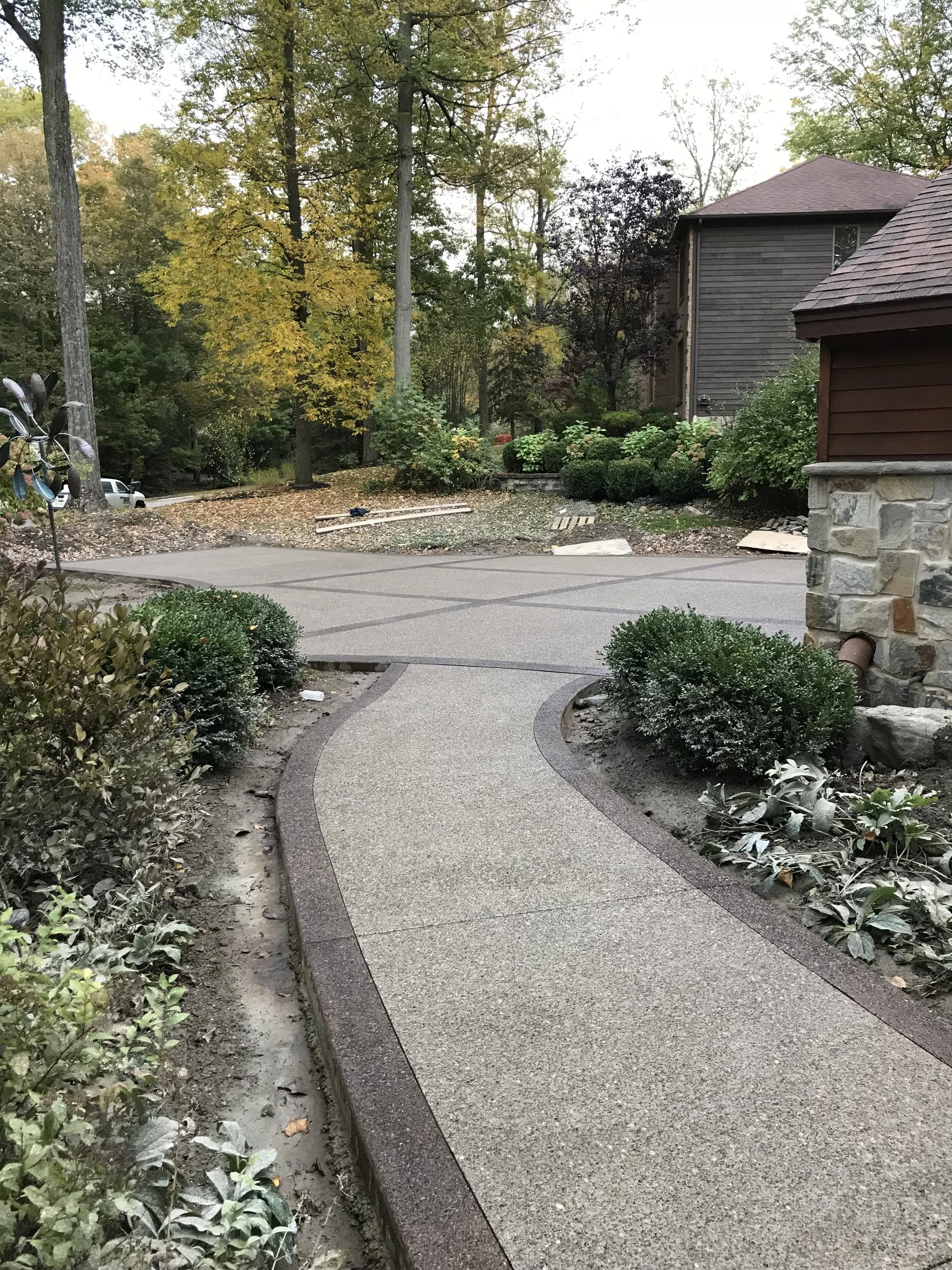 B&amp;W Custom Concrete pathways . A light concrete walkway trimmed with darker concrete. It winds through gardens and connects to a matching patio.